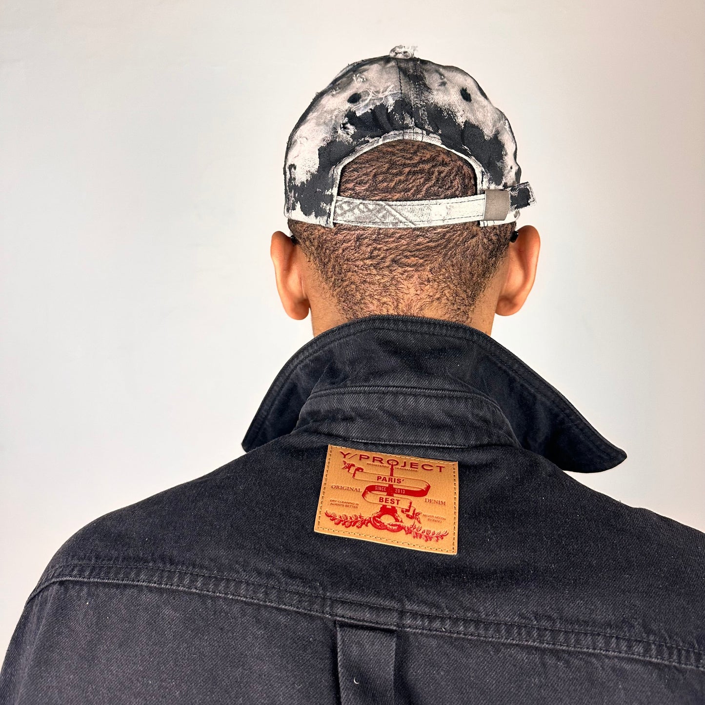 Back of ASTROBOI* white trompe l’oeil denim print hat with blue and black paint, resin accents, and distressed detailing.