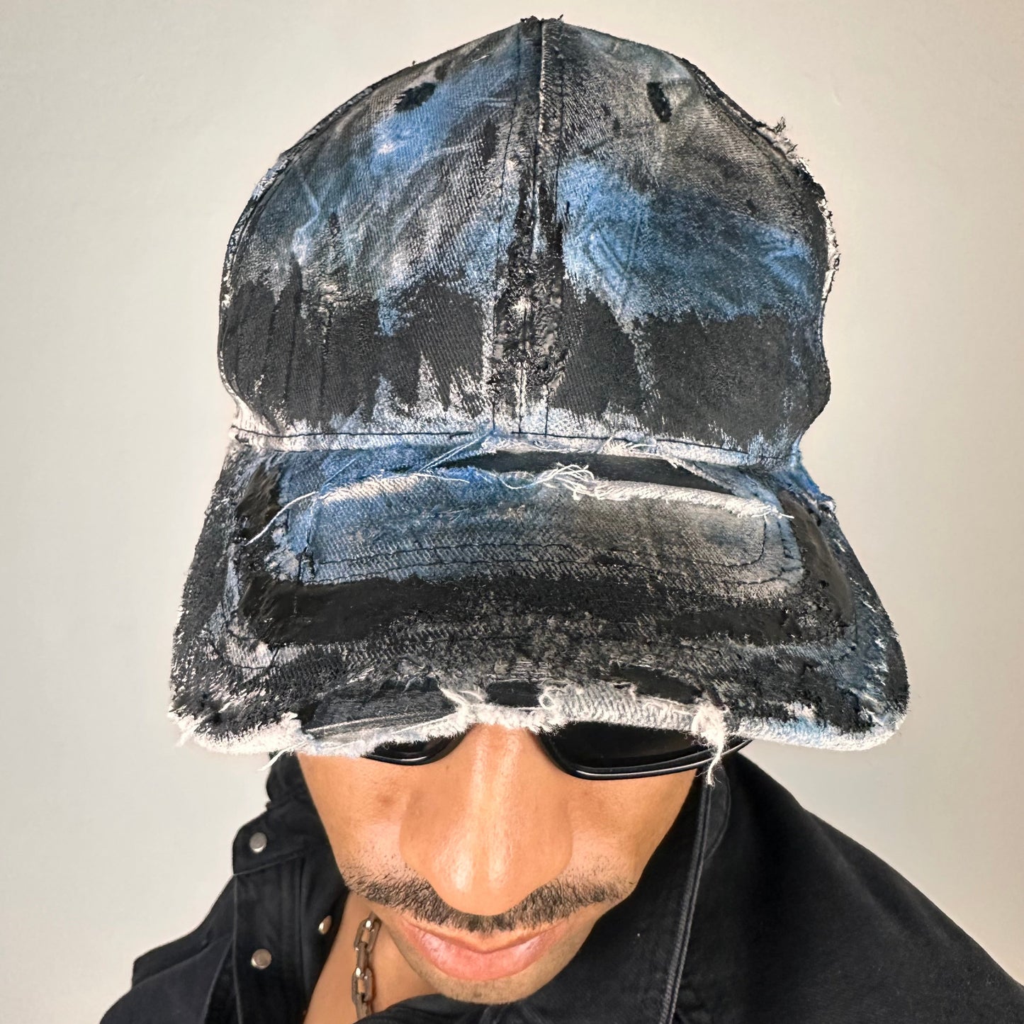 Overview of ASTROBOI* white trompe l’oeil denim print hat with blue and black paint, resin accents, and distressed detailing.