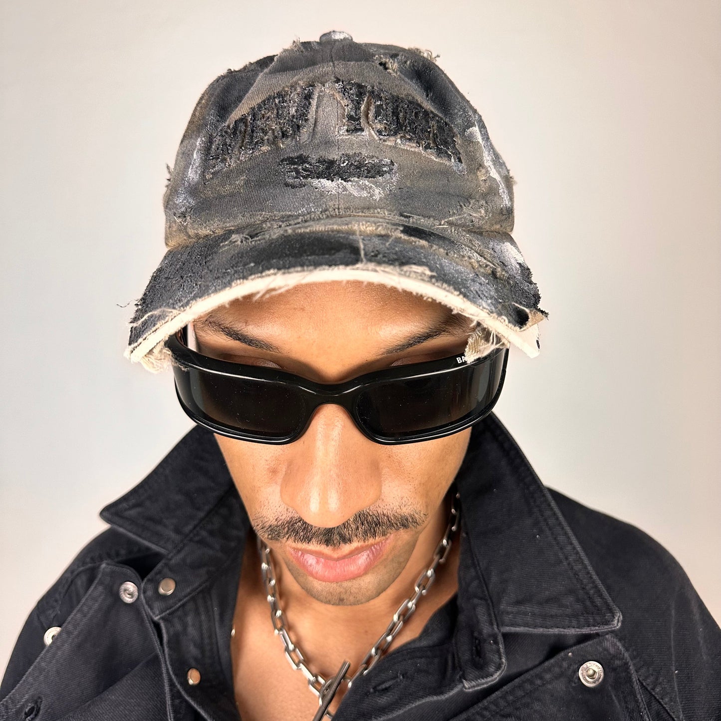 Cover shot of ASTROBOI* tan and black New York logo hat with distressed half visor and black and white paint detailing.