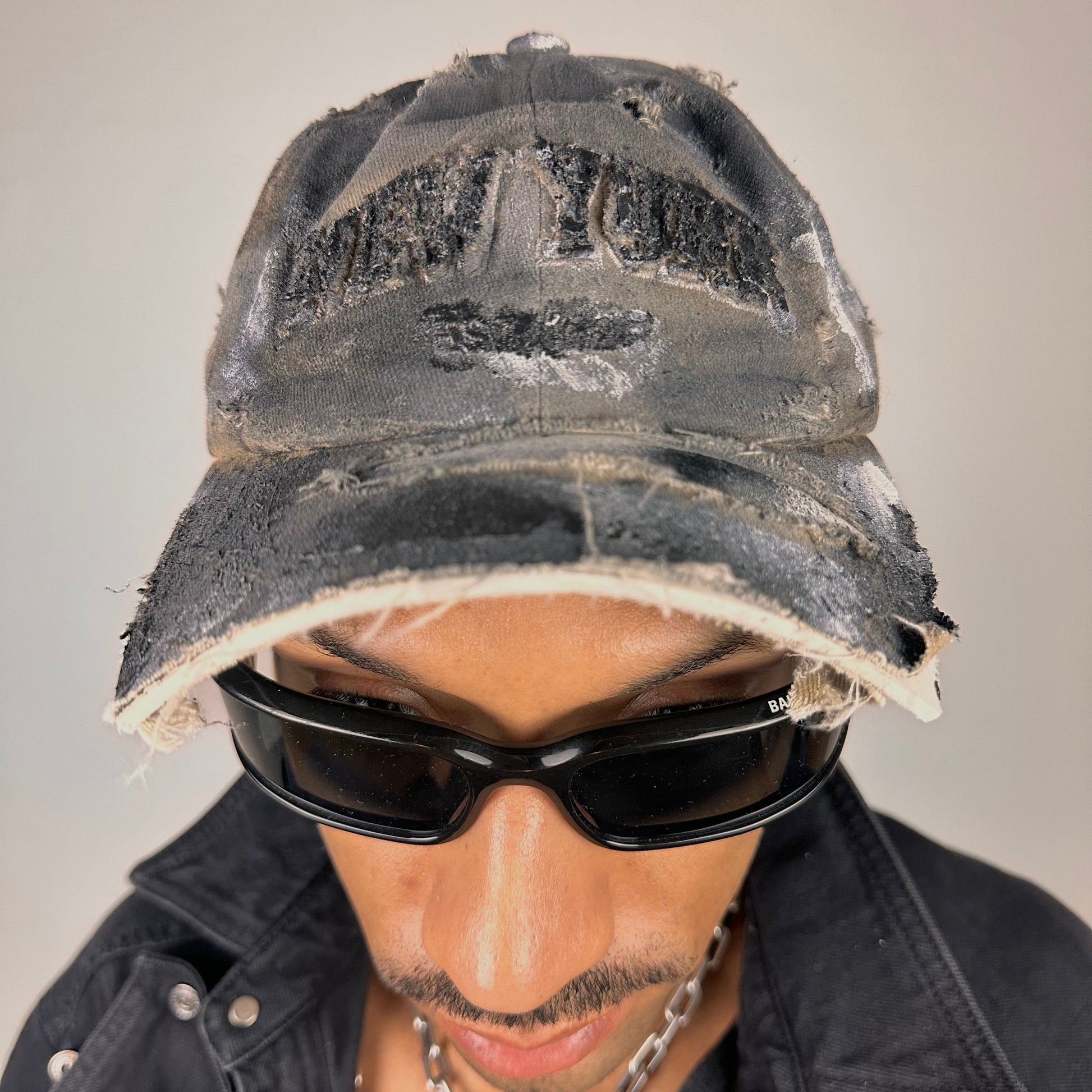 Close up of ASTROBOI* tan and black New York logo hat with distressed half visor and black and white paint detailing.