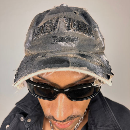 Close up of ASTROBOI* tan and black New York logo hat with distressed half visor and black and white paint detailing.