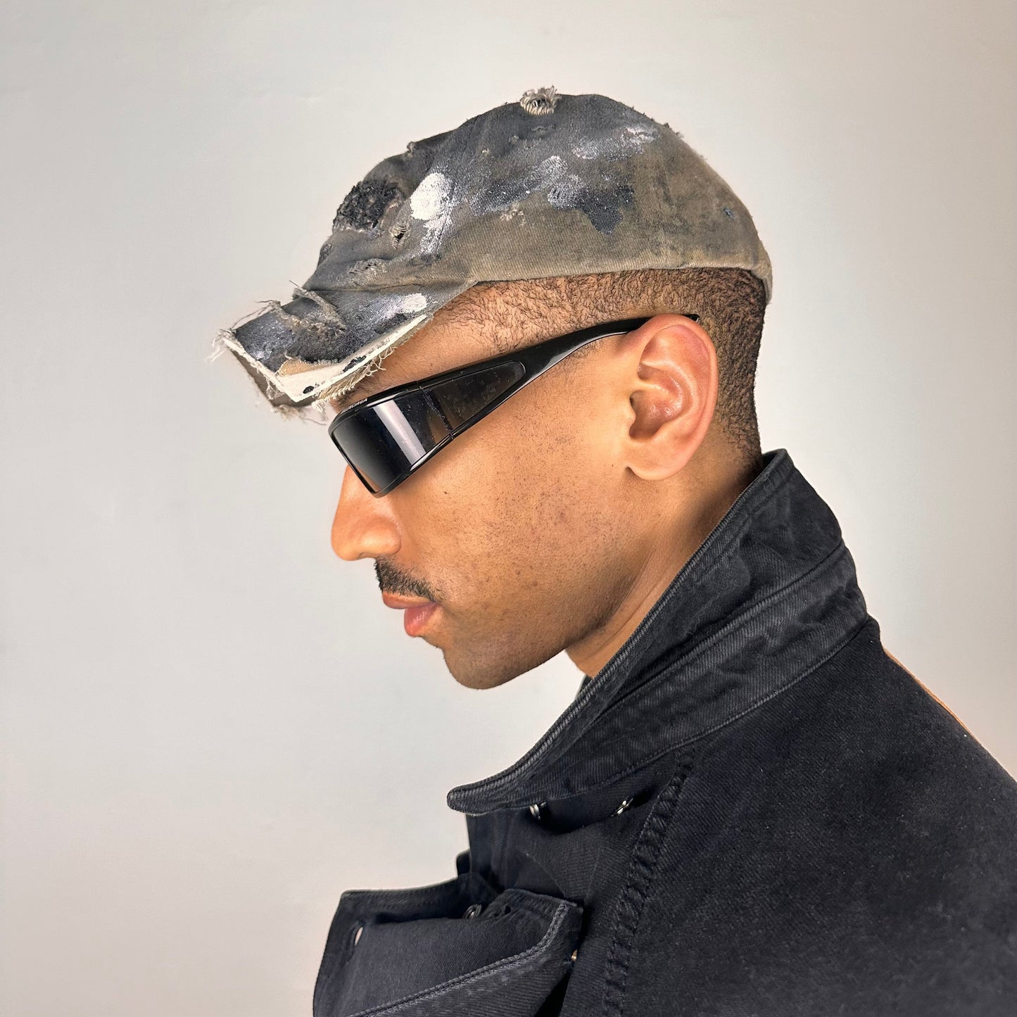 Left side of ASTROBOI* tan and black New York logo hat with distressed half visor and black and white paint detailing.