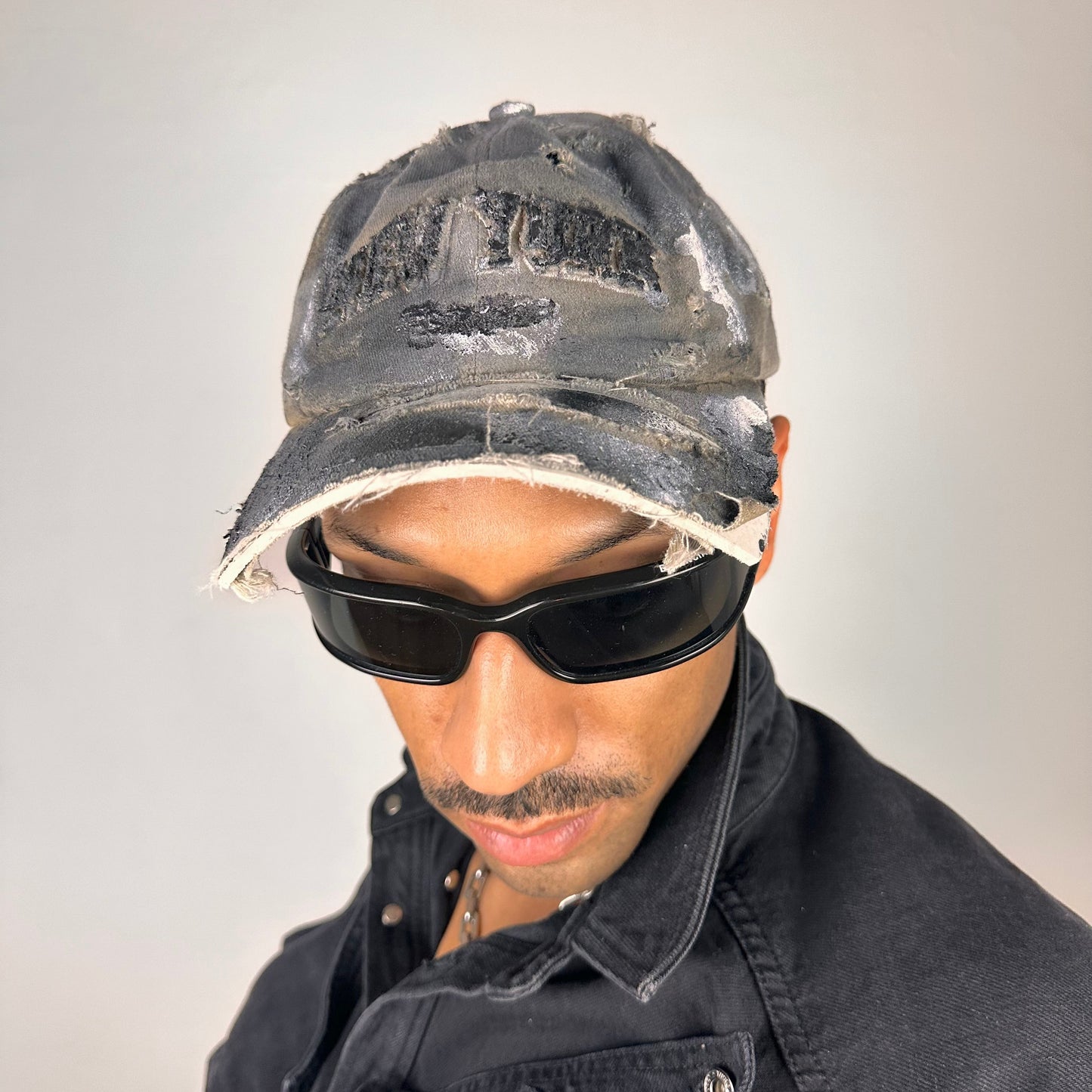 Front styled view of ASTROBOI* tan and black New York logo hat with distressed half visor and black and white paint detailing.