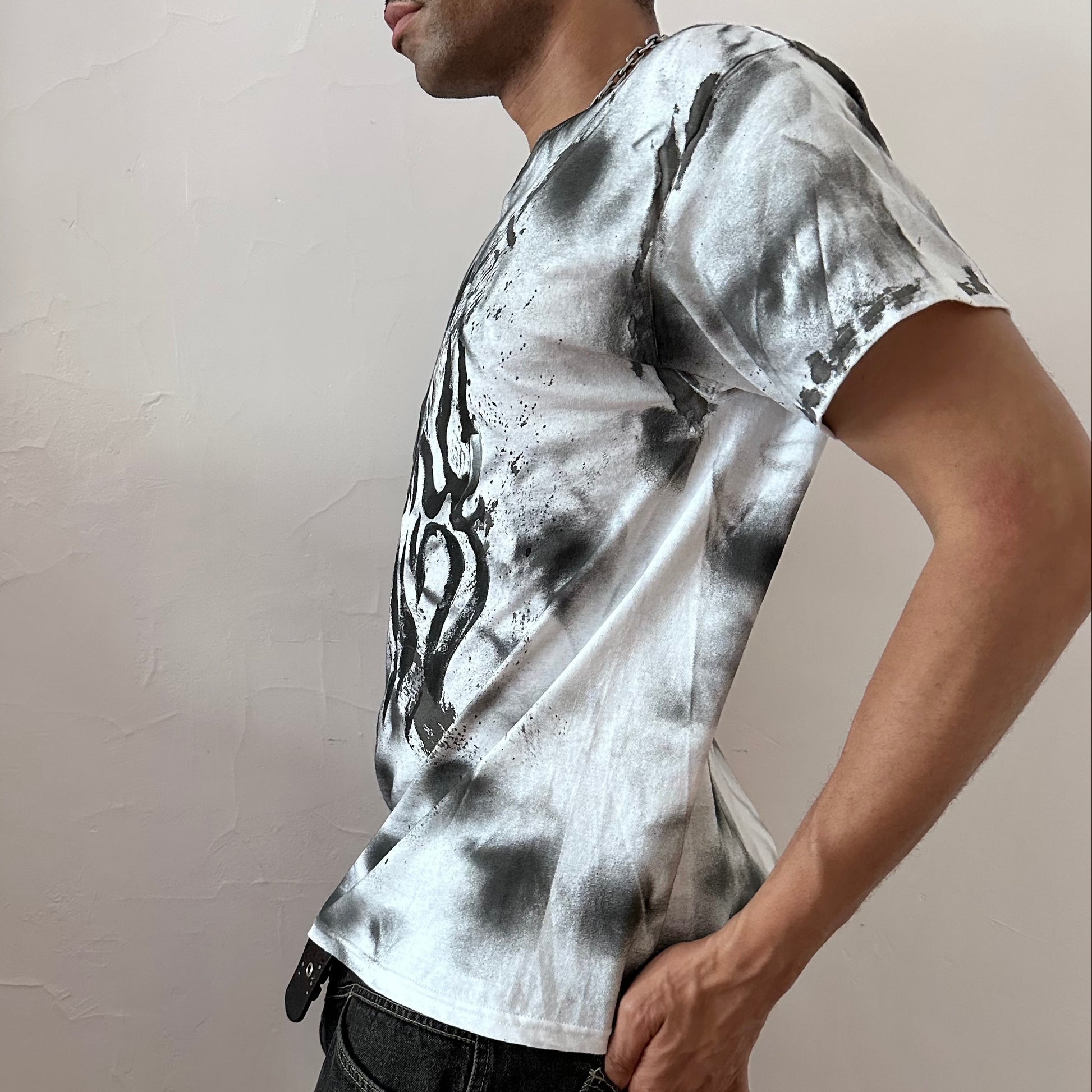 Left side detail of ASTROBOI* x Gildan 'Slither' showing impressionist flame design and black hazy splatter detailing on white graphic tee.