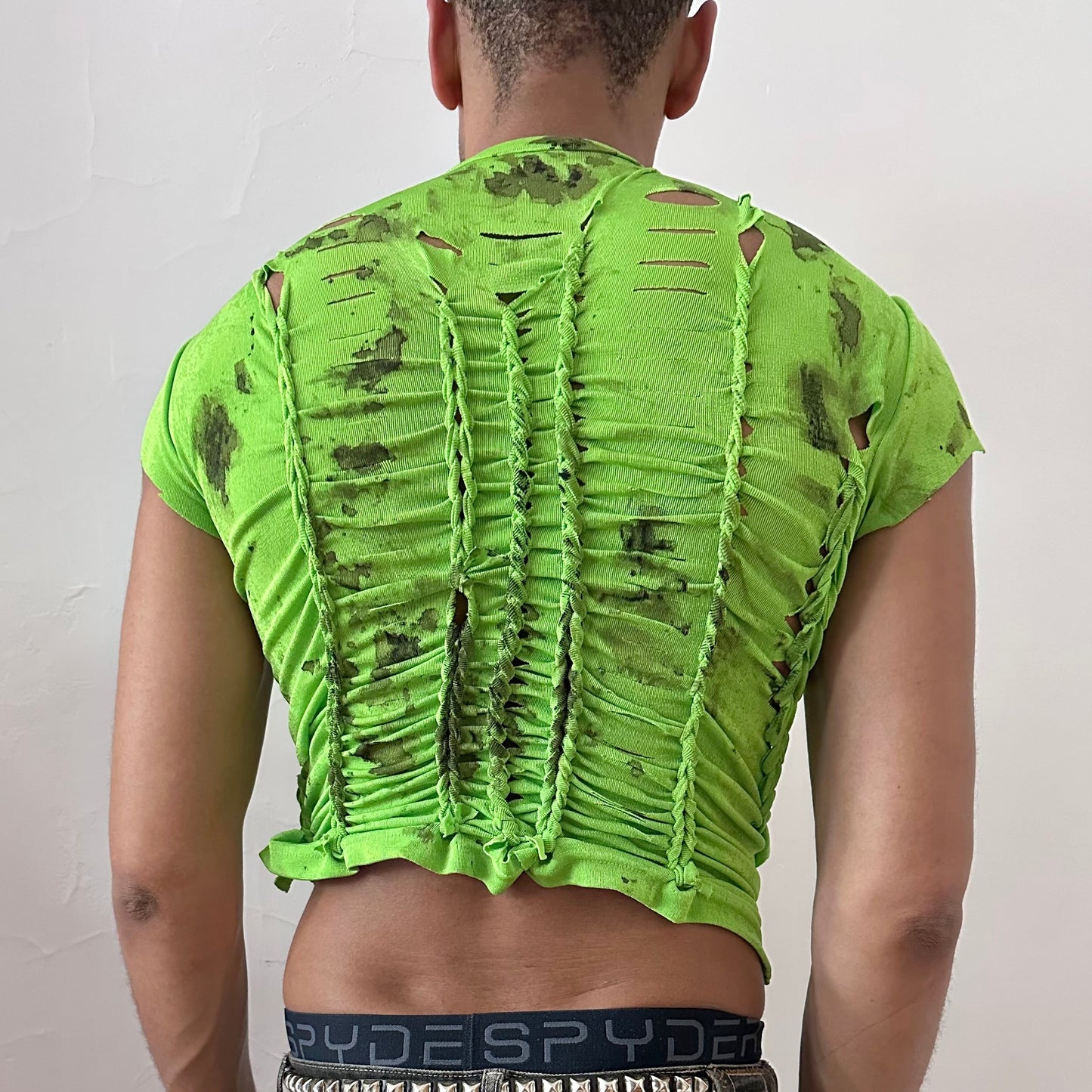ASTROBOI* 'SS26' neon green braided crop t-shirt, rear view showing braid and watercolor paint construction, worn by male model.