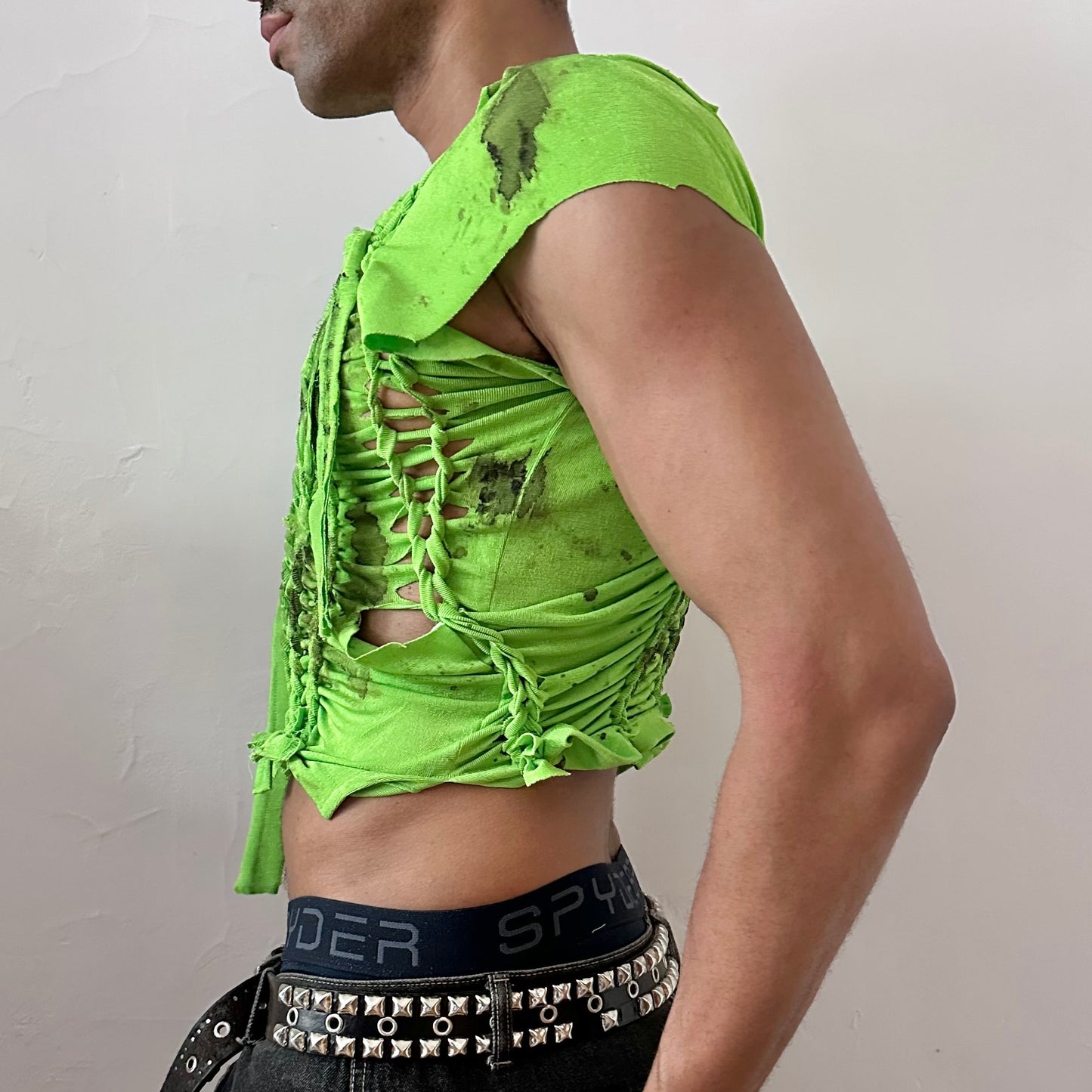 Left side detail of ASTROBOI* 'SS26' showing hand-braided arrangement and black watercolor paint design on cropped neon green stretch tee.