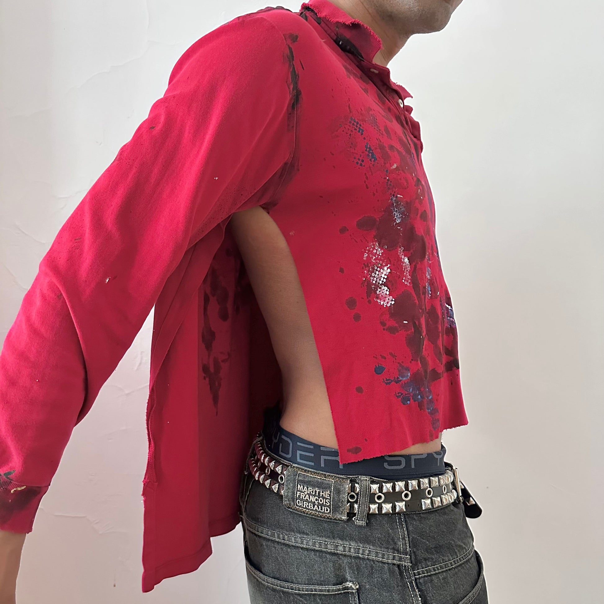  Right side detail of ASTROBOI* x Polo Ralph Lauren 'Kill Switch' showing abstract expressionist paint design and side slit on loose-fitting red base.