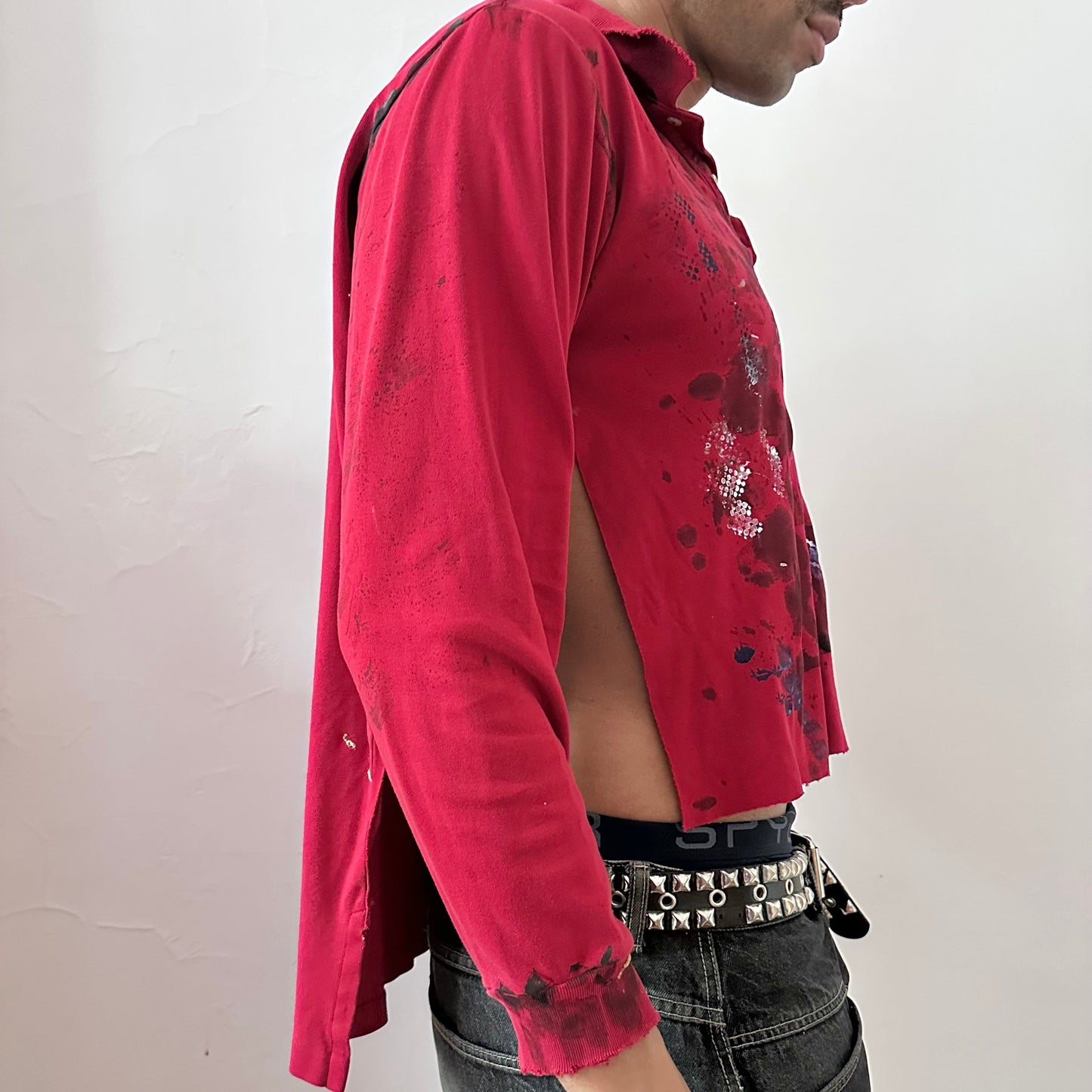  Right side detail of ASTROBOI* x Polo Ralph Lauren 'Kill Switch' showing abstract expressionist paint design and side slit on loose-fitting red base.