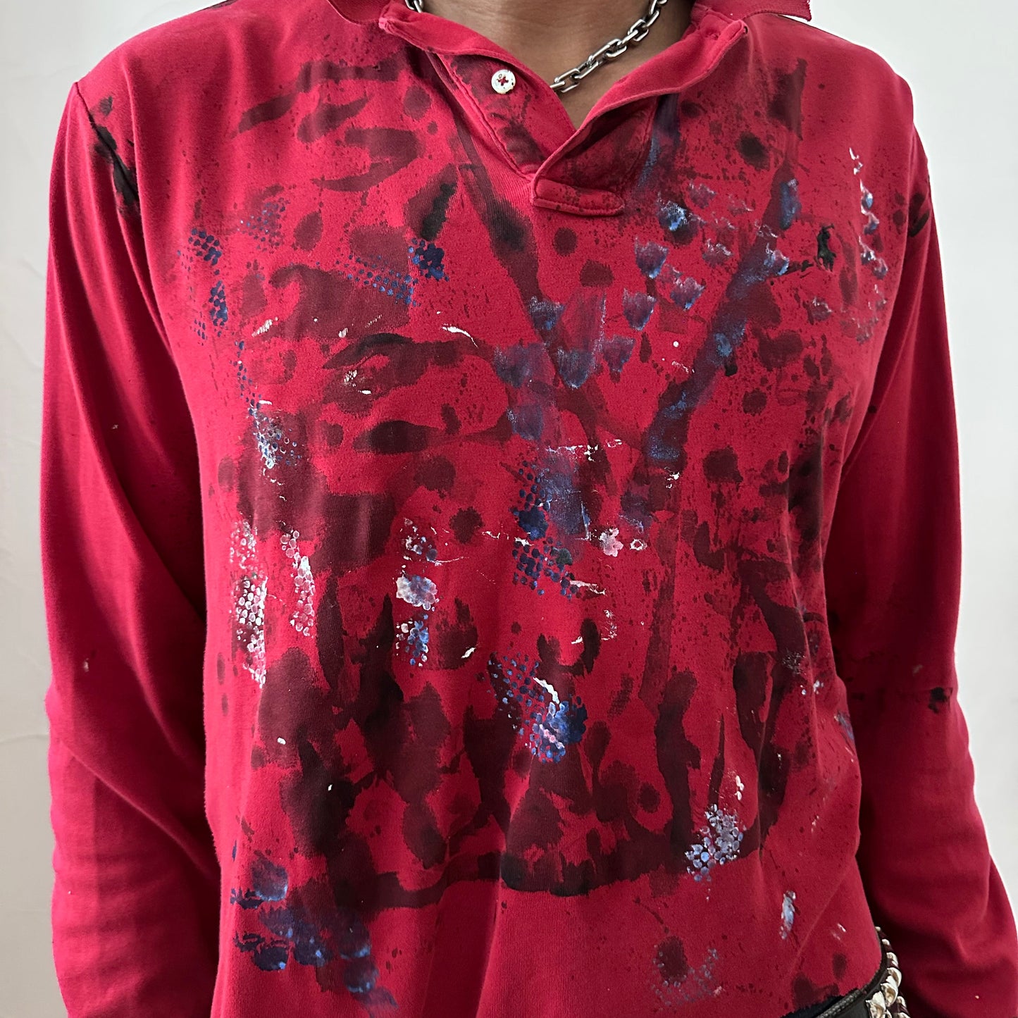 Close-up of ASTROBOI* x Polo Ralph Lauren 'Kill Switch' showing abstract expressionist black, blue, and white paint design and Polo logo detail on red fabric.