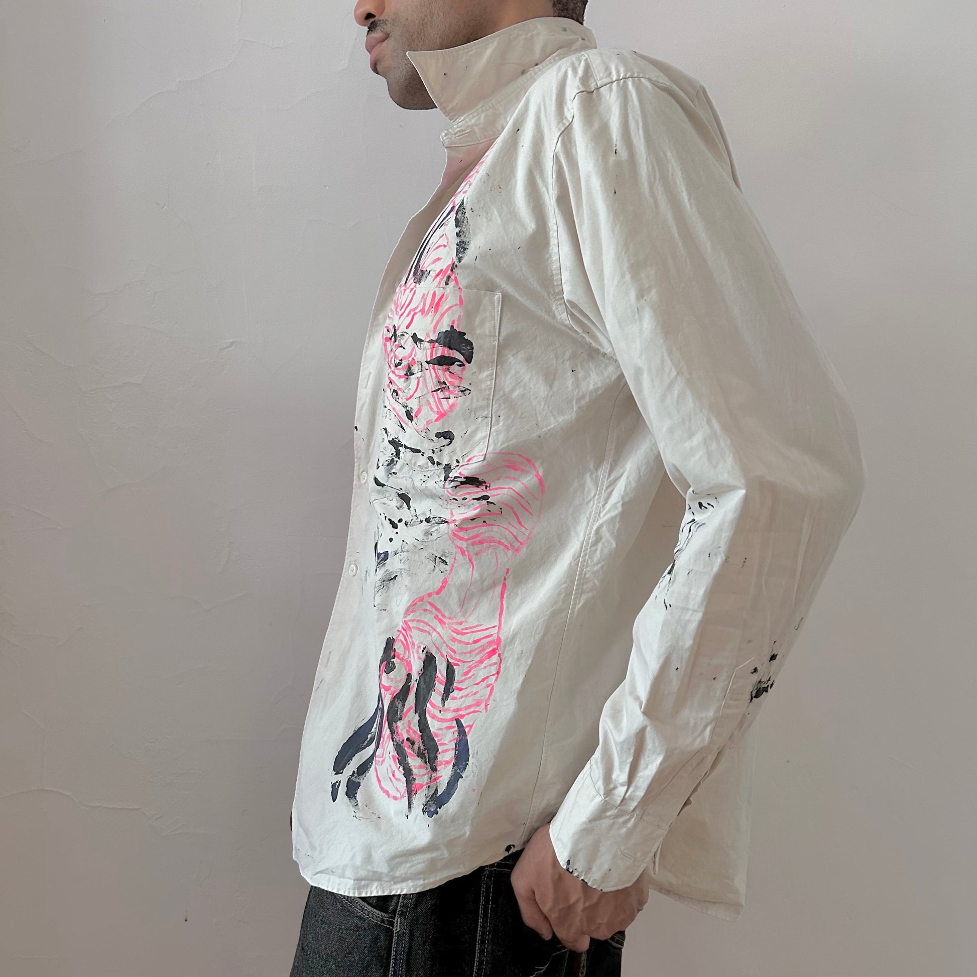 Left side detail of ASTROBOI* x Uniqlo 'Tattoo' showing hand-painted pink abstract design and black expressionist pattern detailing on tan button up.