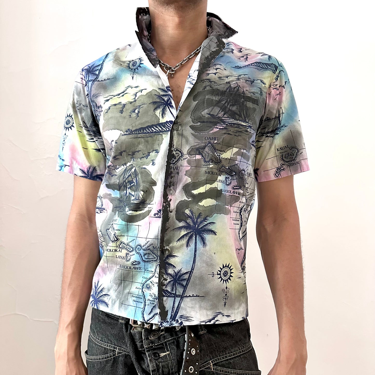 ASTROBOI* 'Sulfur Surfer' white boxy-fit tropical short sleeve button up shirt with custom navy Hawaiian iconography paint treatment throughout and chest pocket at right, front view.