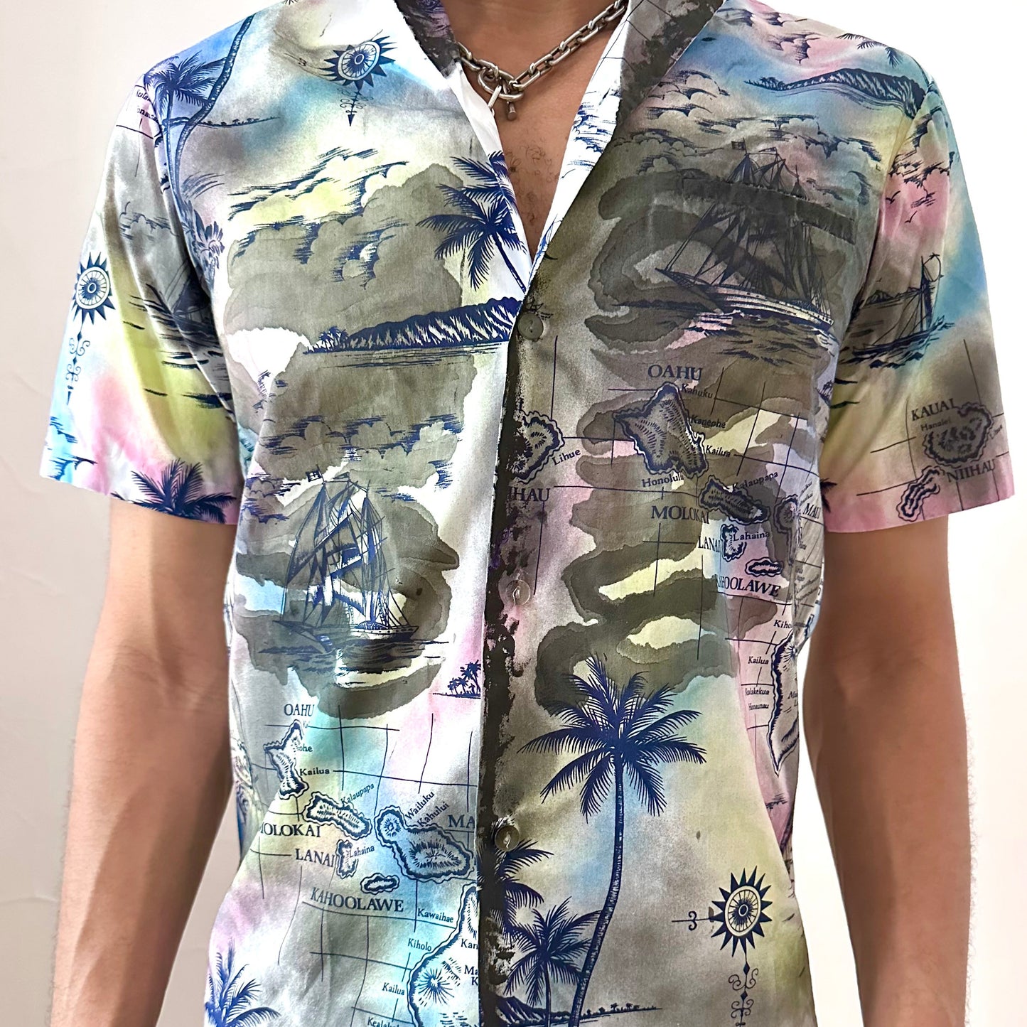 Close-up of ASTROBOI* 'Sulfur Surfer' showing hand-painted navy Hawaiian iconography detail and chest pocket on white cotton fabric.