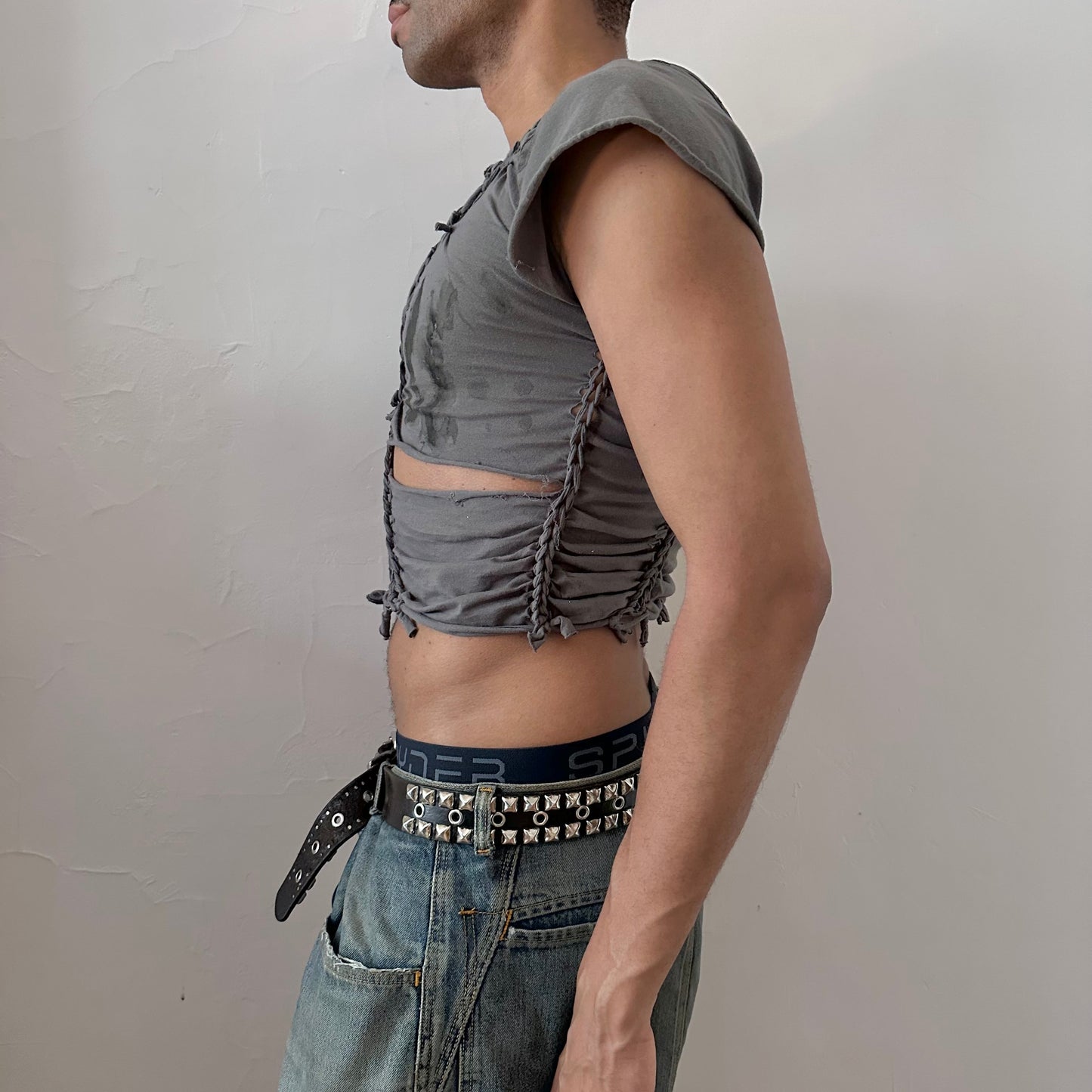 Left side detail of ASTROBOI* 'Waverly' showing hand-braided arrangement, slash detail, and faded tattoo print on gray crop tee.