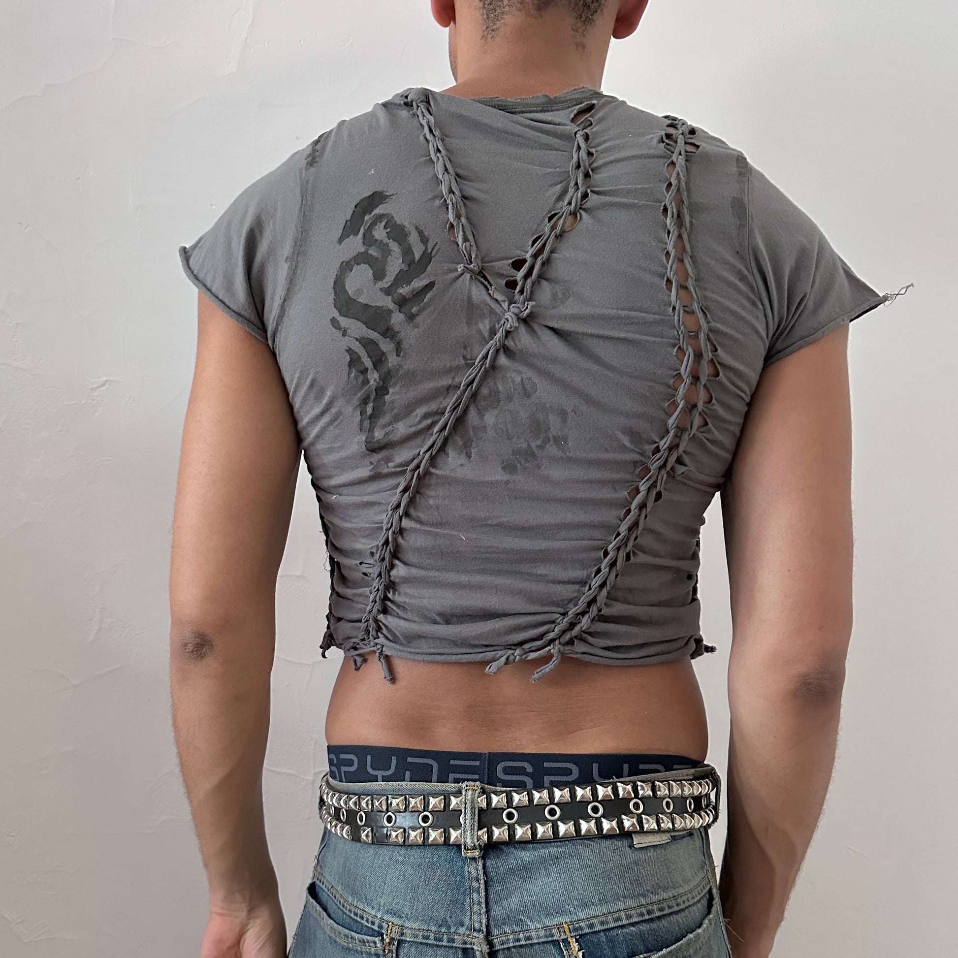 ASTROBOI* 'Waverly' gray tattoo braided festival crop t-shirt, rear view showing braid, slash, and faded tattoo print on back, worn by male model.