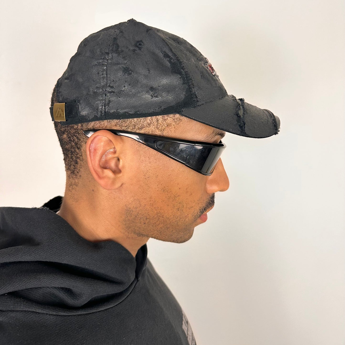 Right side of ASTROBOI* x Chevy black distressed baseball hat with resin-sealed rhinestone logo, deconstructed visor, wax-painted tattoo details, adjustable fit