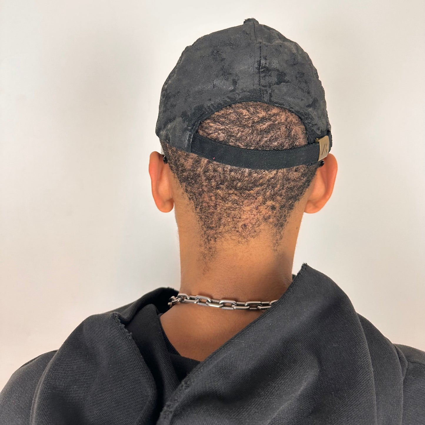 Back of ASTROBOI* x Chevy black distressed baseball hat with resin-sealed rhinestone logo, deconstructed visor, wax-painted tattoo details, adjustable fit