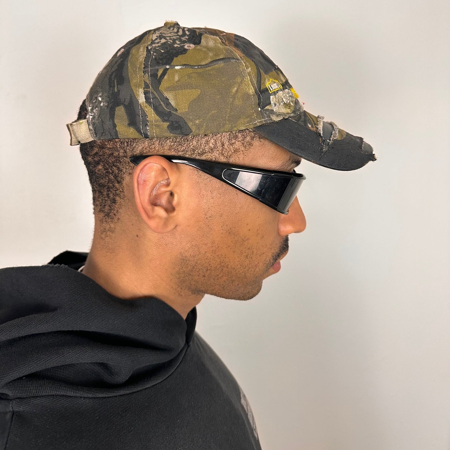 Right side of ASTROBOI* x Lowe’s MVP brown RealTree camouflage hat with resin-sealed rhinestone logo, black waxed tattoo print, adjustable strap, custom NYC piece
