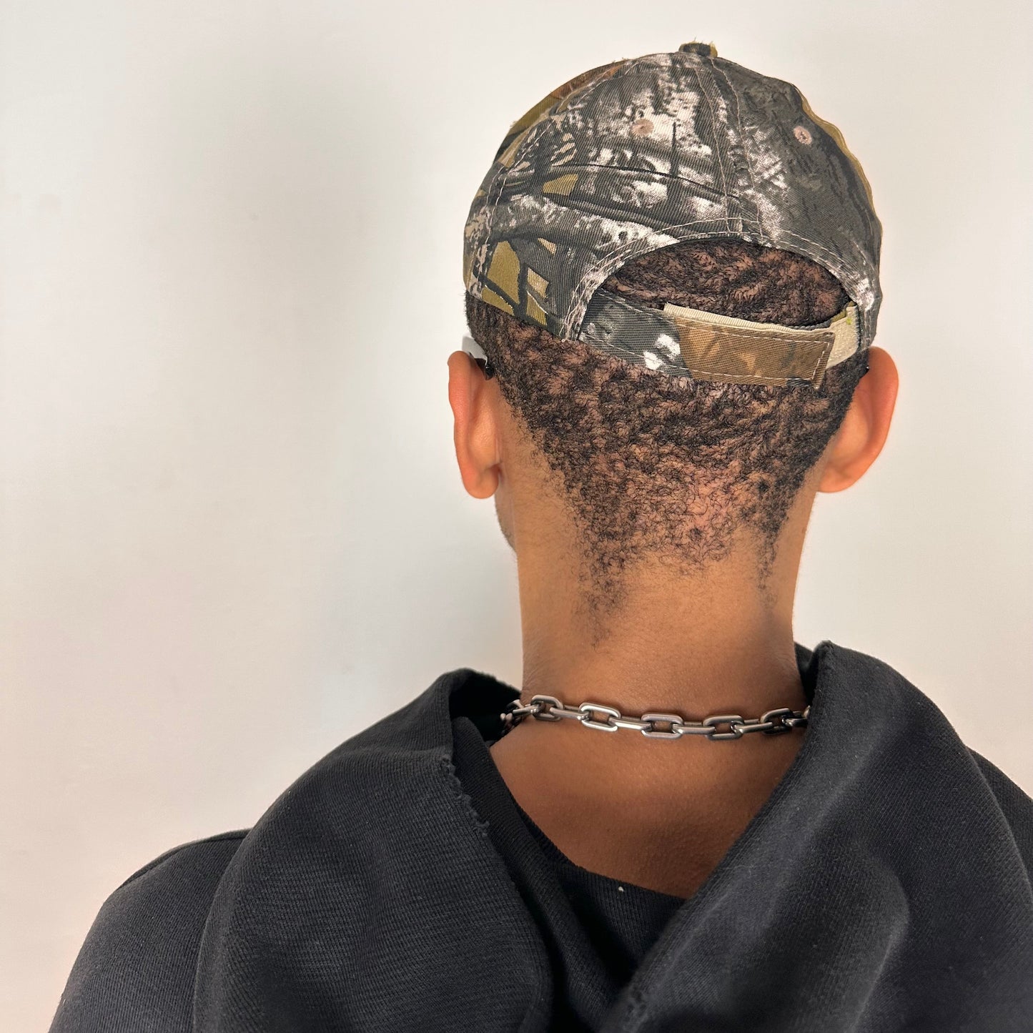 Back of ASTROBOI* x Lowe’s MVP brown RealTree camouflage hat with resin-sealed rhinestone logo, black waxed tattoo print, adjustable strap, custom NYC piece