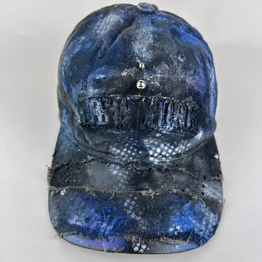 ASTROBOI* 'North Star' black and blue distressed painted hat with "New York" embroidery and black, white, and blue hand-painted design, front view.