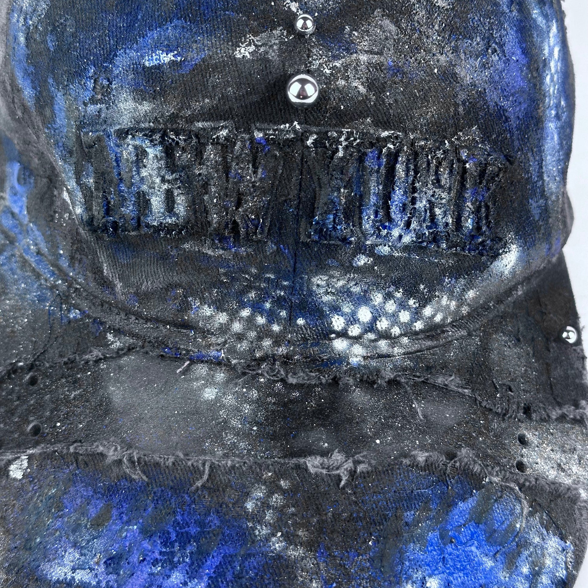 Close-up of ASTROBOI* 'North Star' showing "New York" embroidery detail and black, white, and blue distressed paint design.