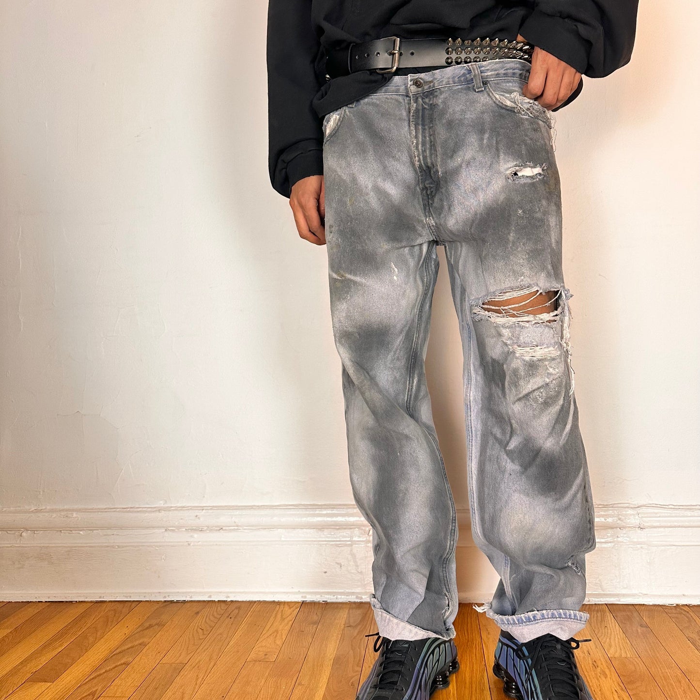 Front of ASTROBOI* light rinse blue tar jeans with baggy fit, distressed cotton denim, and black and clay paint detailing, size 36x32