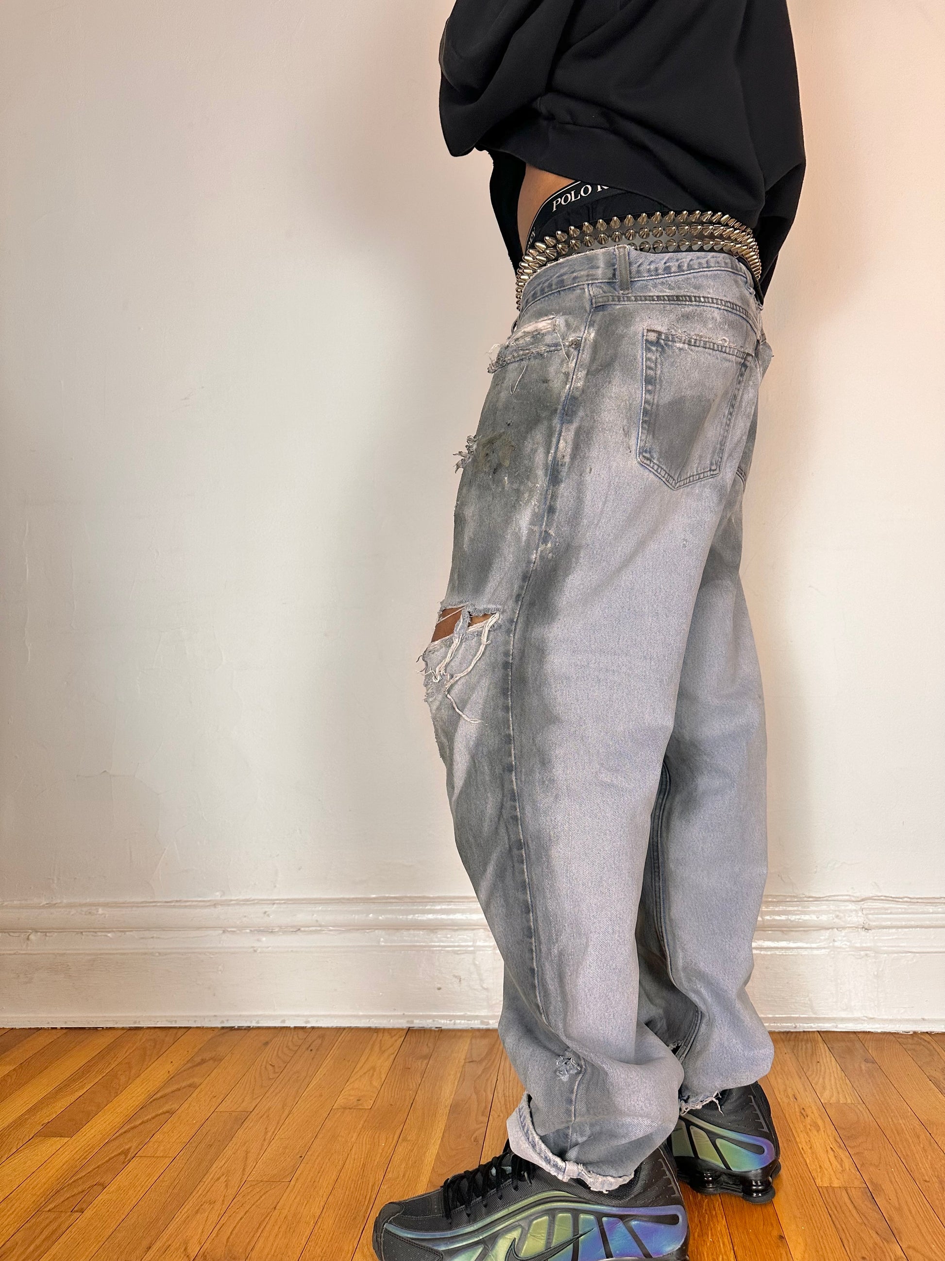 Left side of ASTROBOI* light rinse blue tar jeans with baggy fit, distressed cotton denim, and black and clay paint detailing, size 36x32