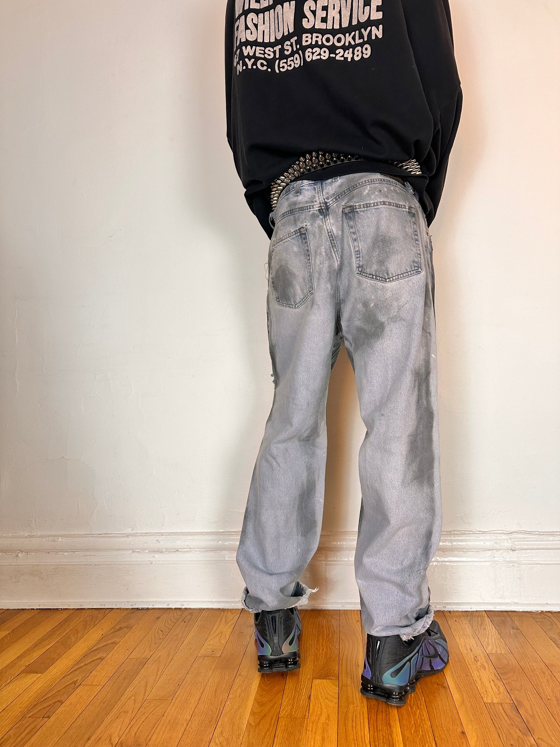 Back side of ASTROBOI* light rinse blue tar jeans with baggy fit, distressed cotton denim, and black and clay paint detailing, size 36x32