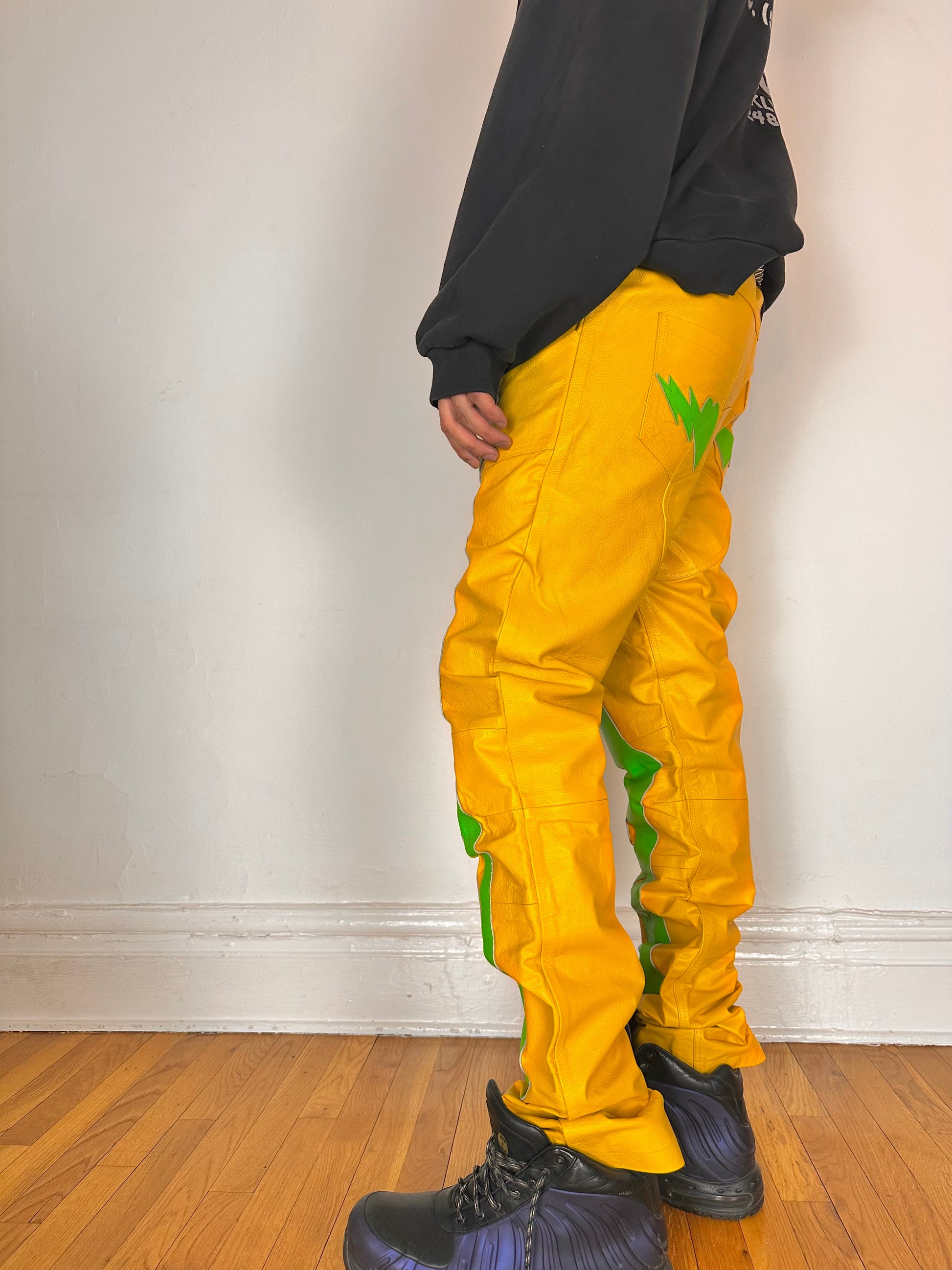 Left side of Seeking green and yellow skeleton leather biker pants featuring a straight leg fit, bold skeleton detailing, and branded back patch. Size 36x36.