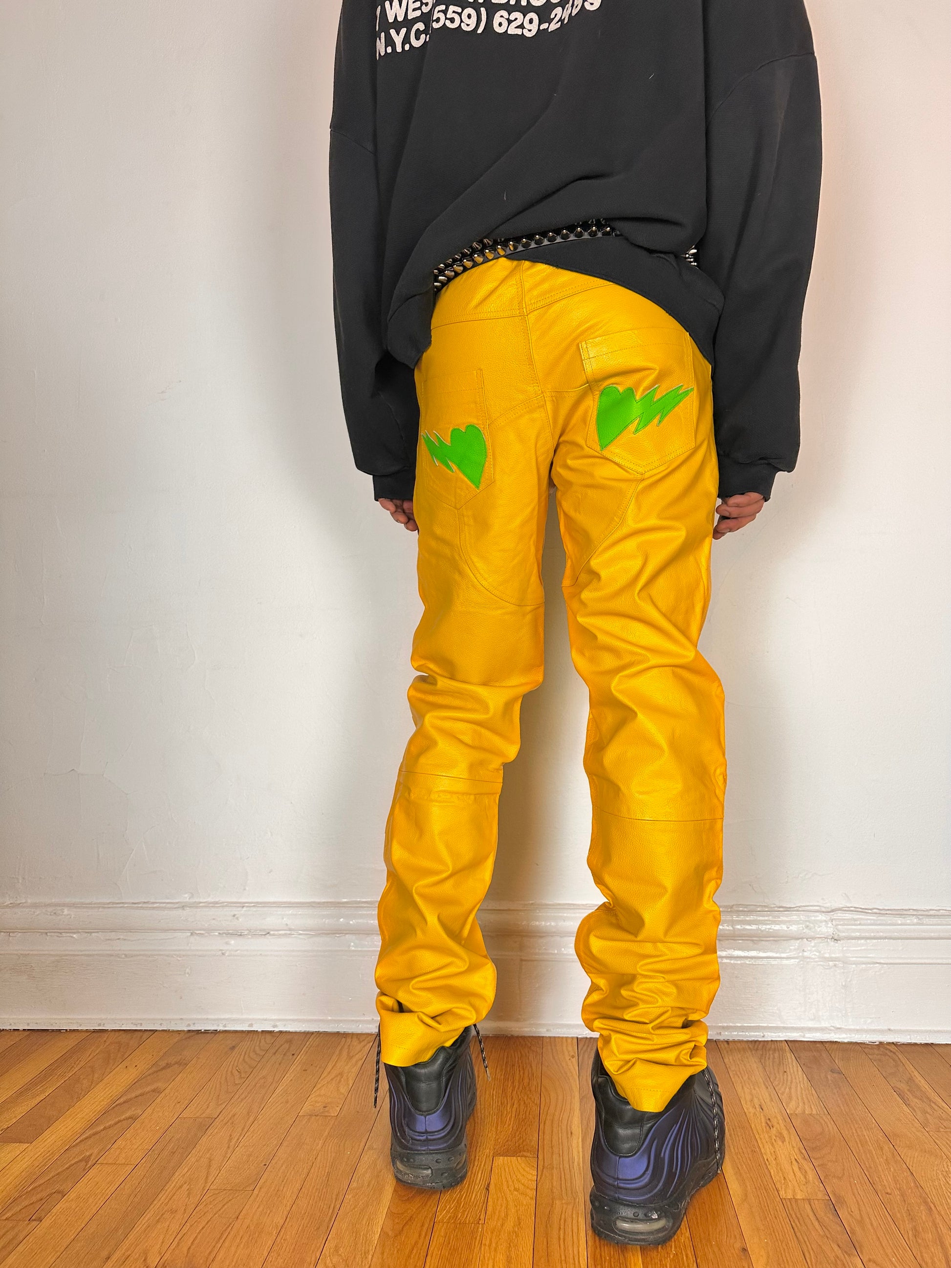 Back side of Seeking green and yellow skeleton leather biker pants featuring a straight leg fit, bold skeleton detailing, and branded back patch. Size 36x36.