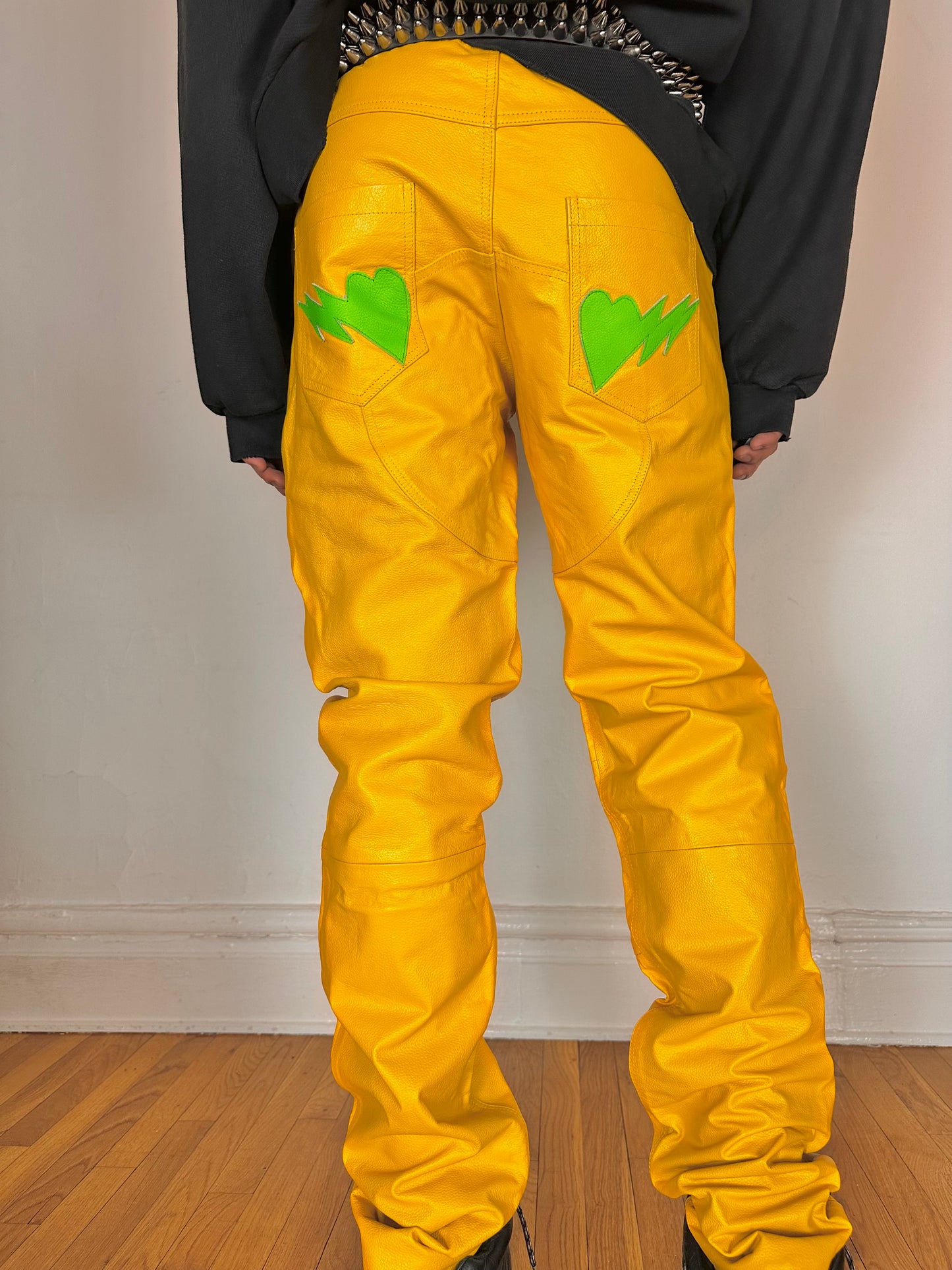 Close up of back pockets on Seeking green and yellow skeleton leather biker pants featuring a straight leg fit, bold skeleton detailing, and branded back patch. Size 36x36.