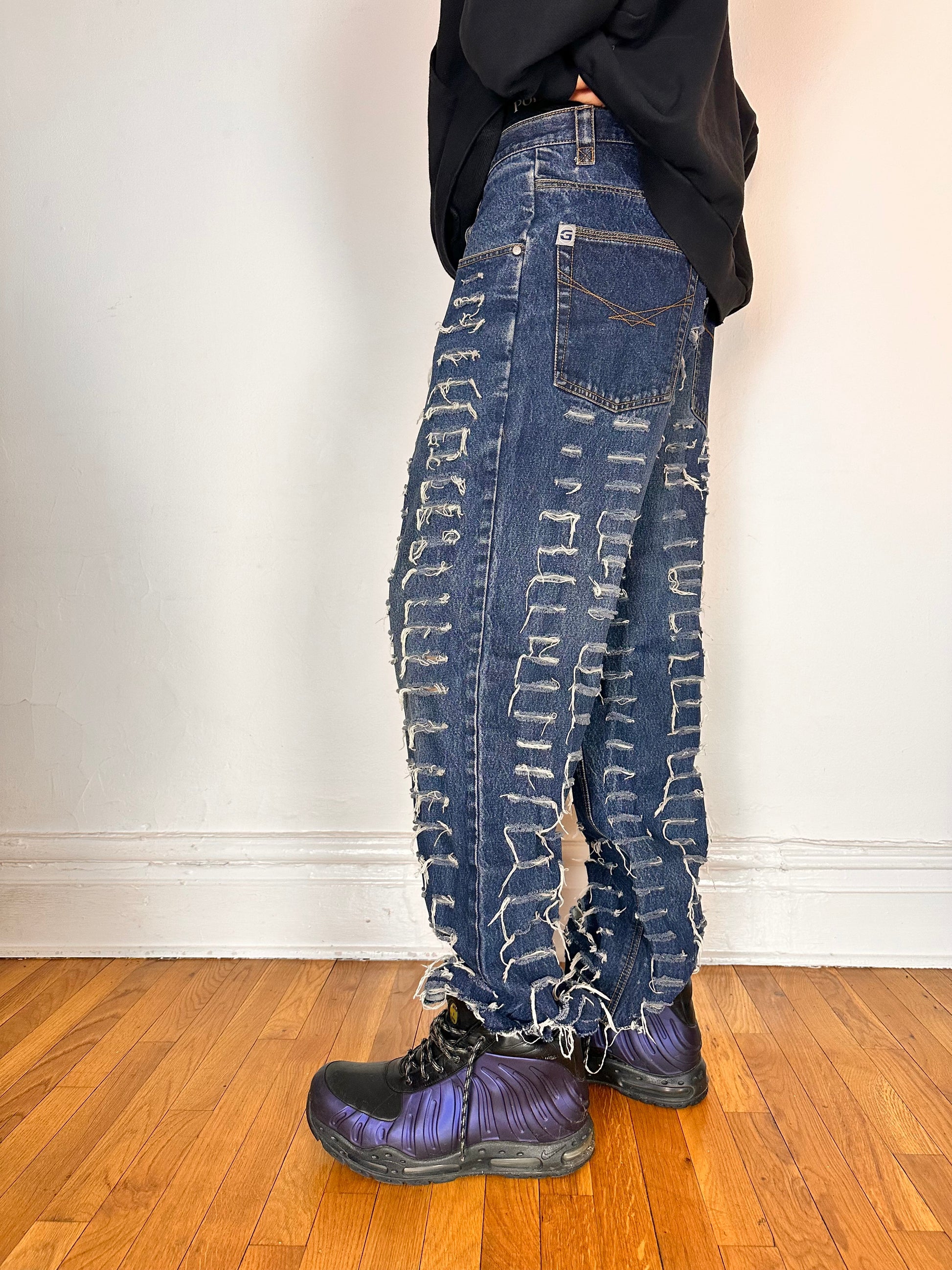 Left side of ASTROBOI* blue slashed grunge faded ripped jeans with thigh and leg slashes, relaxed leg fit, size 31x34, customized in NYC