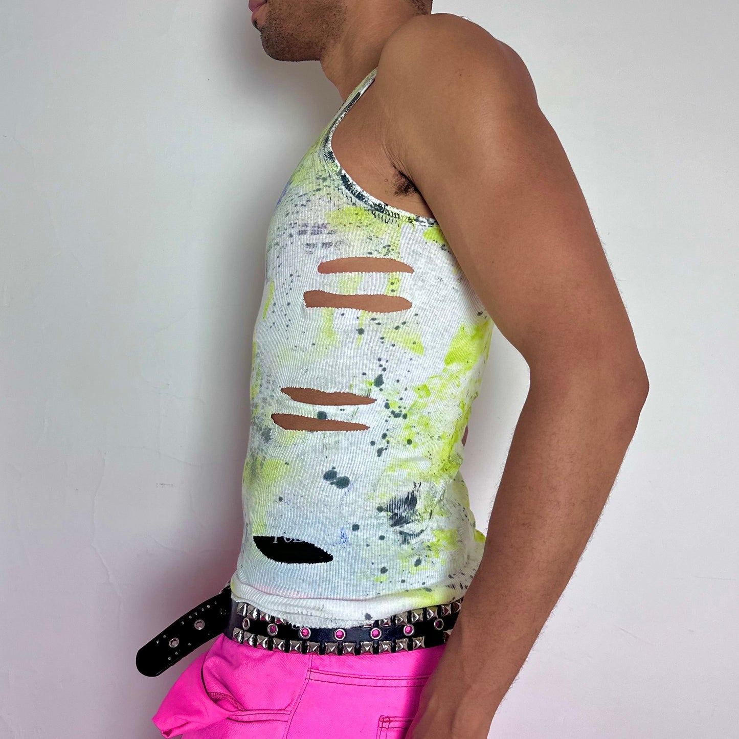 Left side detail of ASTROBOI* x Gildan 'Blitz' showing side cut-out, digital camo design, and black and ultraviolet splatter on white tank.
