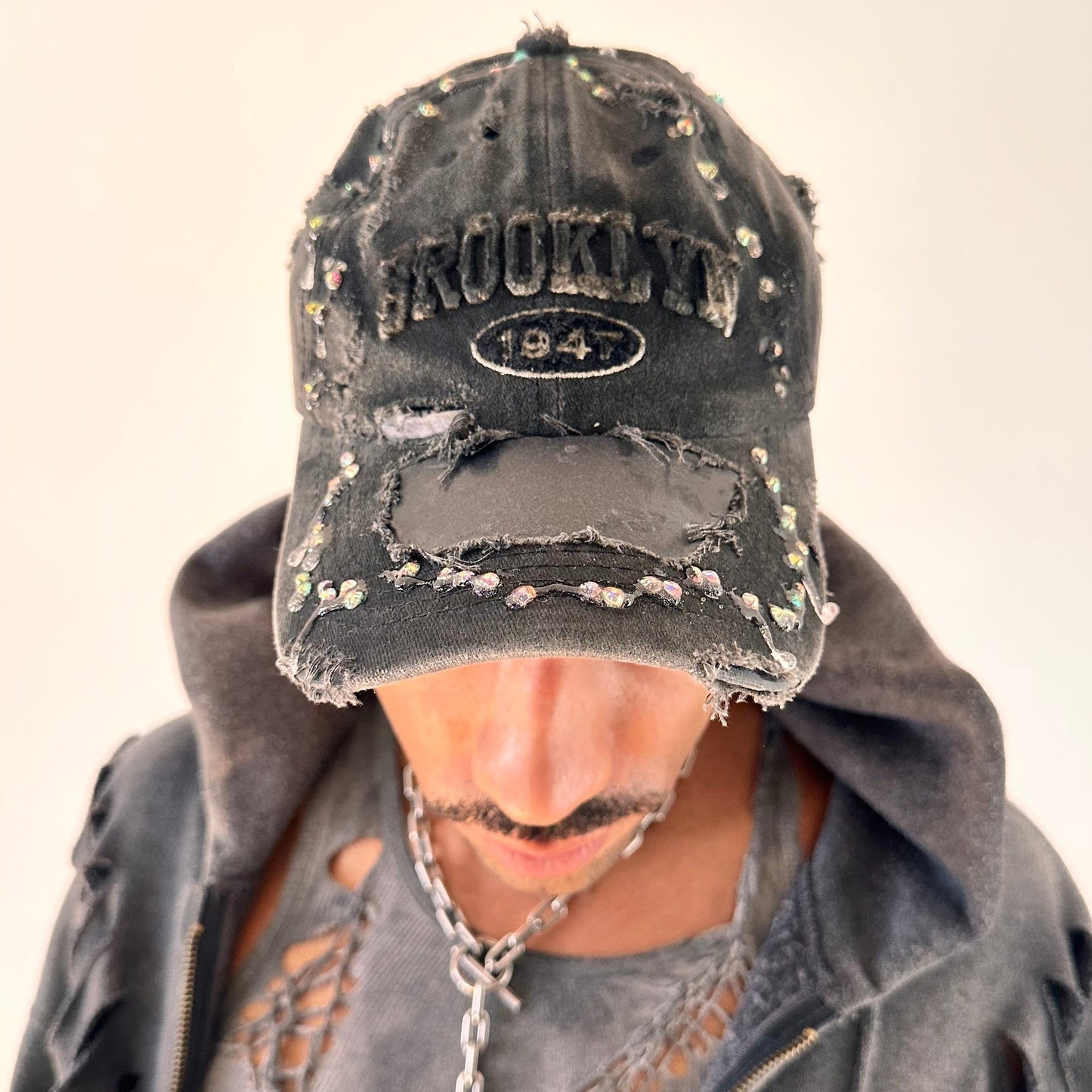 Styled image of ASTROBOI* Moon Crystals Brooklyn black distressed hat with multicolored rhinestones sealed in resin and black airbrush paint treatment