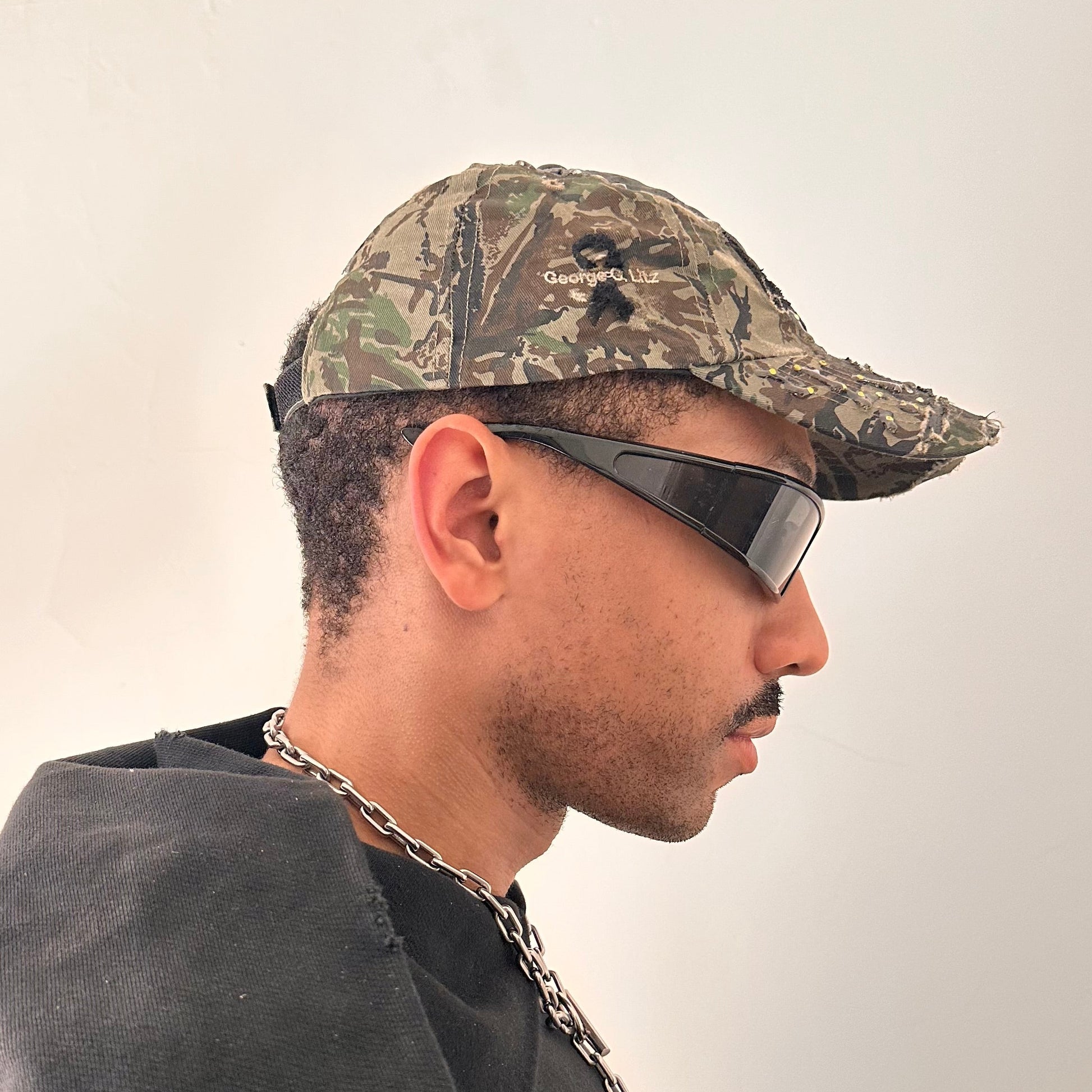 Right side of ASTROBOI* L&L Supply green RealTree camo utility hat with purple and green rhinestones sealed in resin and black tattoo print detailing