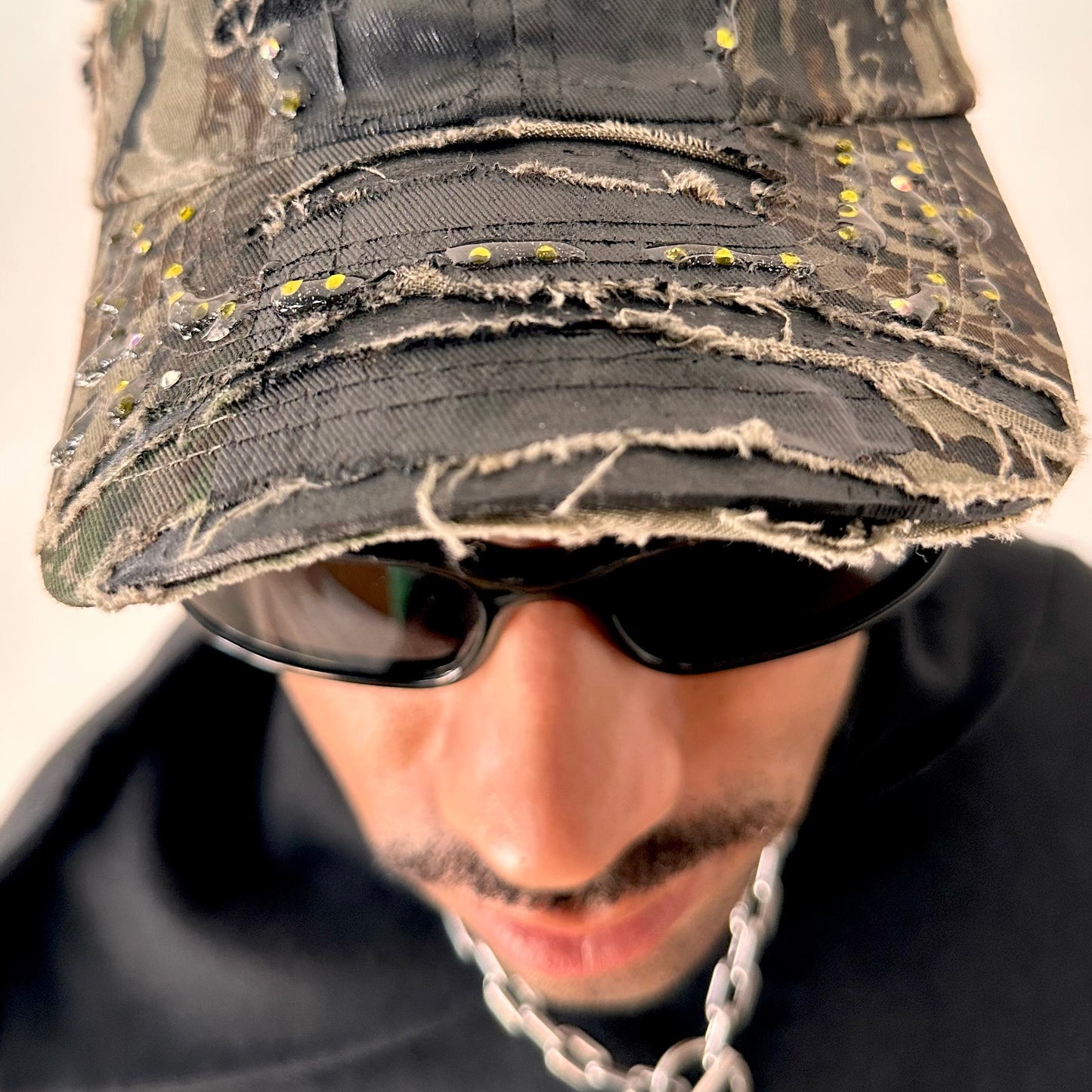 Visor close up on ASTROBOI* L&L Supply green RealTree camo utility hat with purple and green rhinestones sealed in resin and black tattoo print detailing