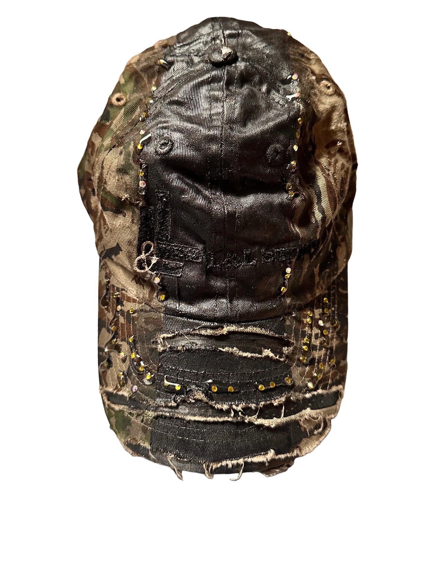 Product shot of ASTROBOI* L&L Supply green RealTree camo utility hat with purple and green rhinestones sealed in resin and black tattoo print detailing