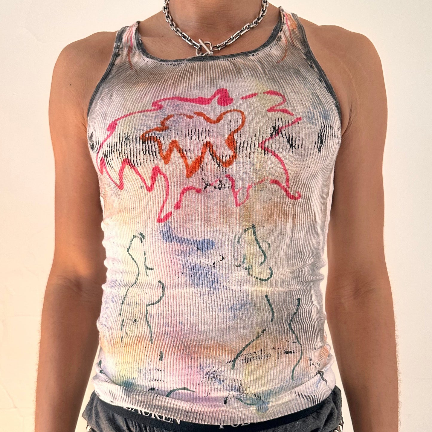Close-up of ASTROBOI* x Hanes 'HEAVEN' showing hand-painted multicolored graffiti detail and hazy rainbow color wash on white ribbed fabric.