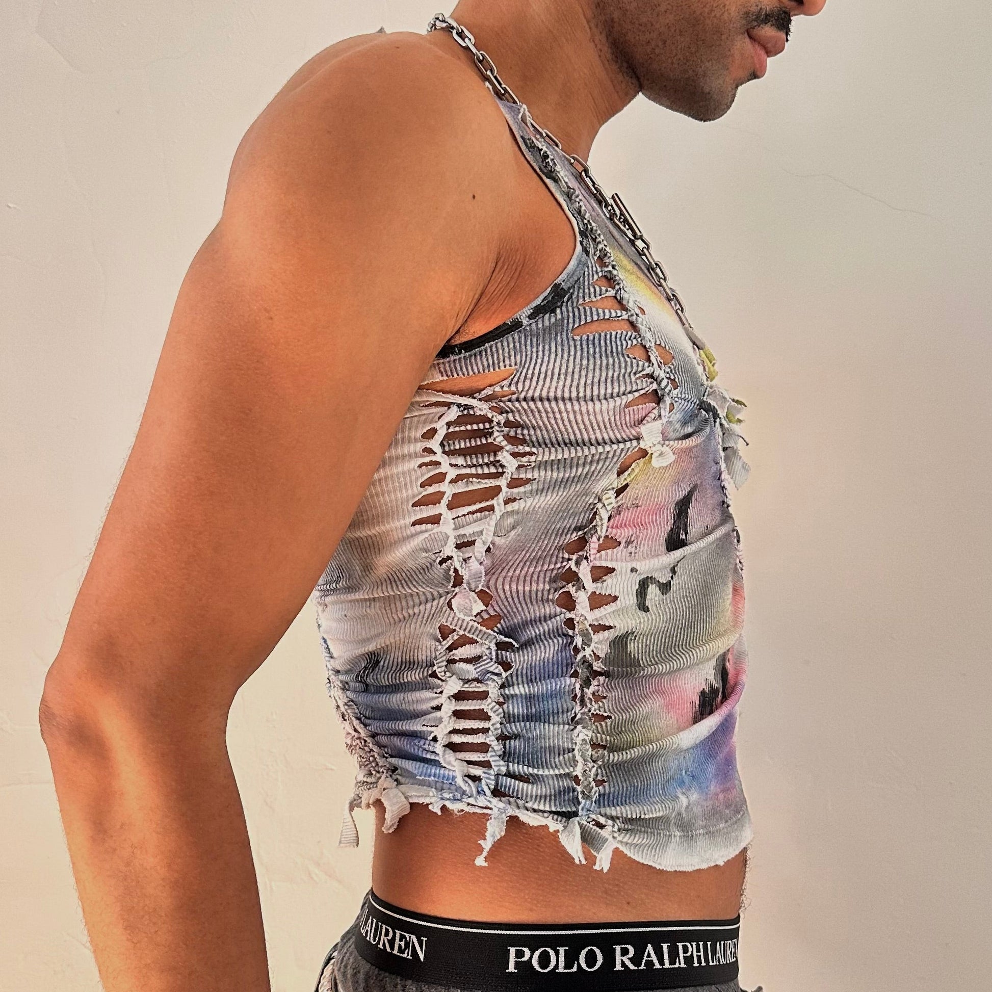 Right side detail of ASTROBOI* x Calvin Klein 'Tri Color' showing braided twist, slash construction, and rainbow multicolor watercolor paint detailing on white base.