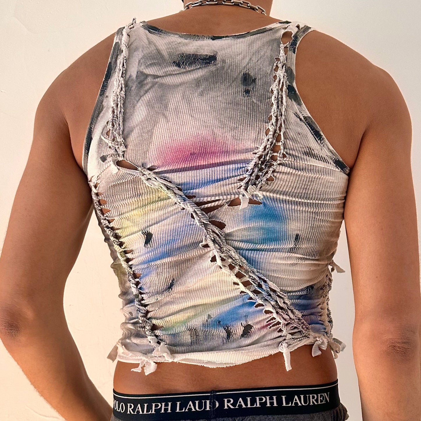 ASTROBOI* x Calvin Klein 'Tri Color' white braided twist tank top, rear view showing braid, slash, raw hem, and watercolor paint detail, worn by male model.