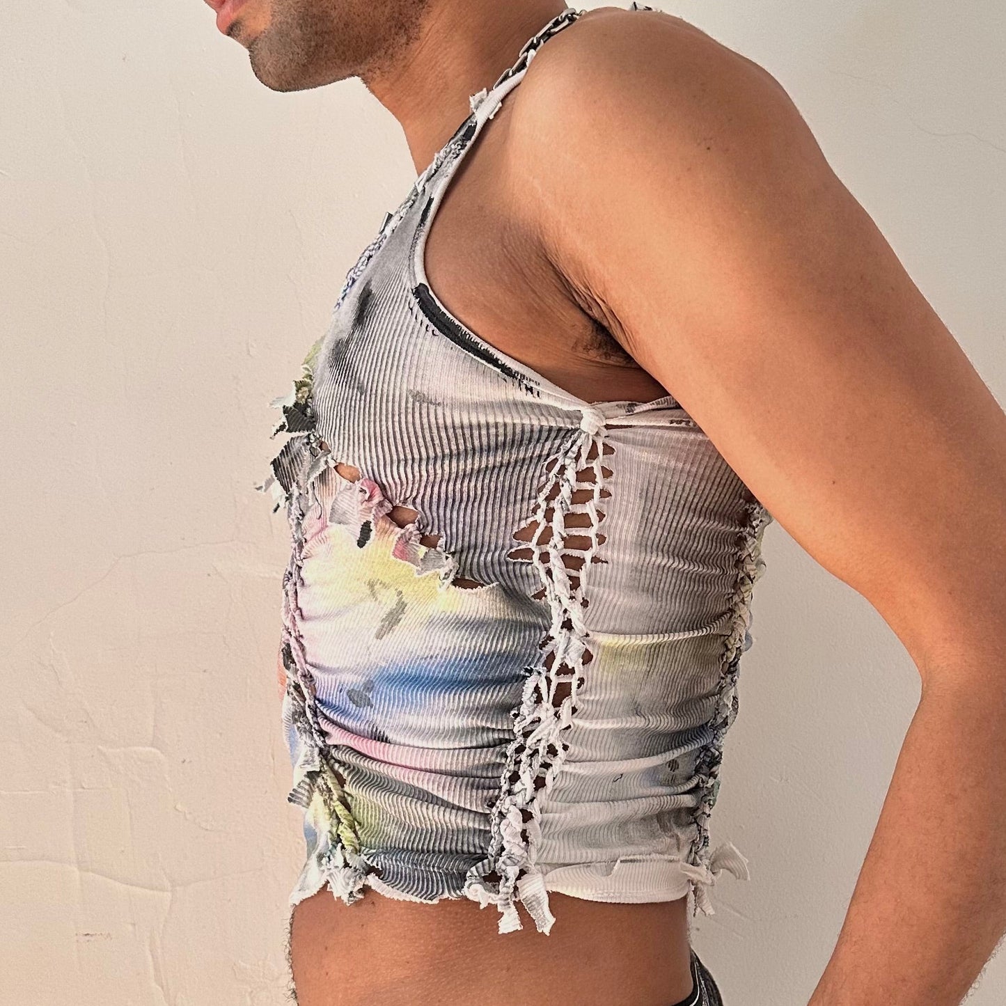 Left side detail of ASTROBOI* x Calvin Klein 'Tri Color' showing hand-braided arrangement, raw hem, and watercolor paint design on white cotton tank.