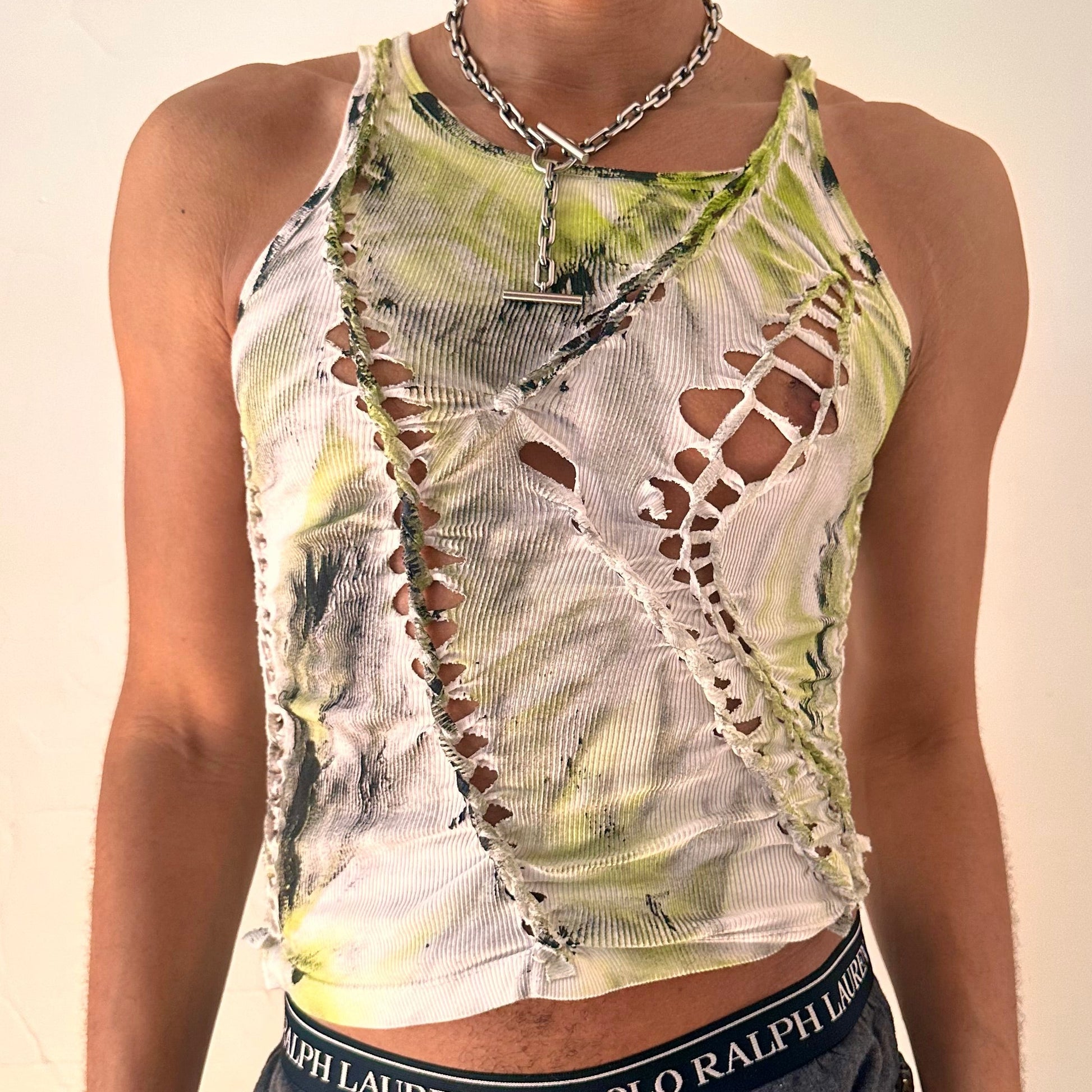 Close-up of ASTROBOI* x Calvin Klein 'Brat' showing hand-braided construction, slash detail, raw hem finish, and green black haze paint on white cotton.