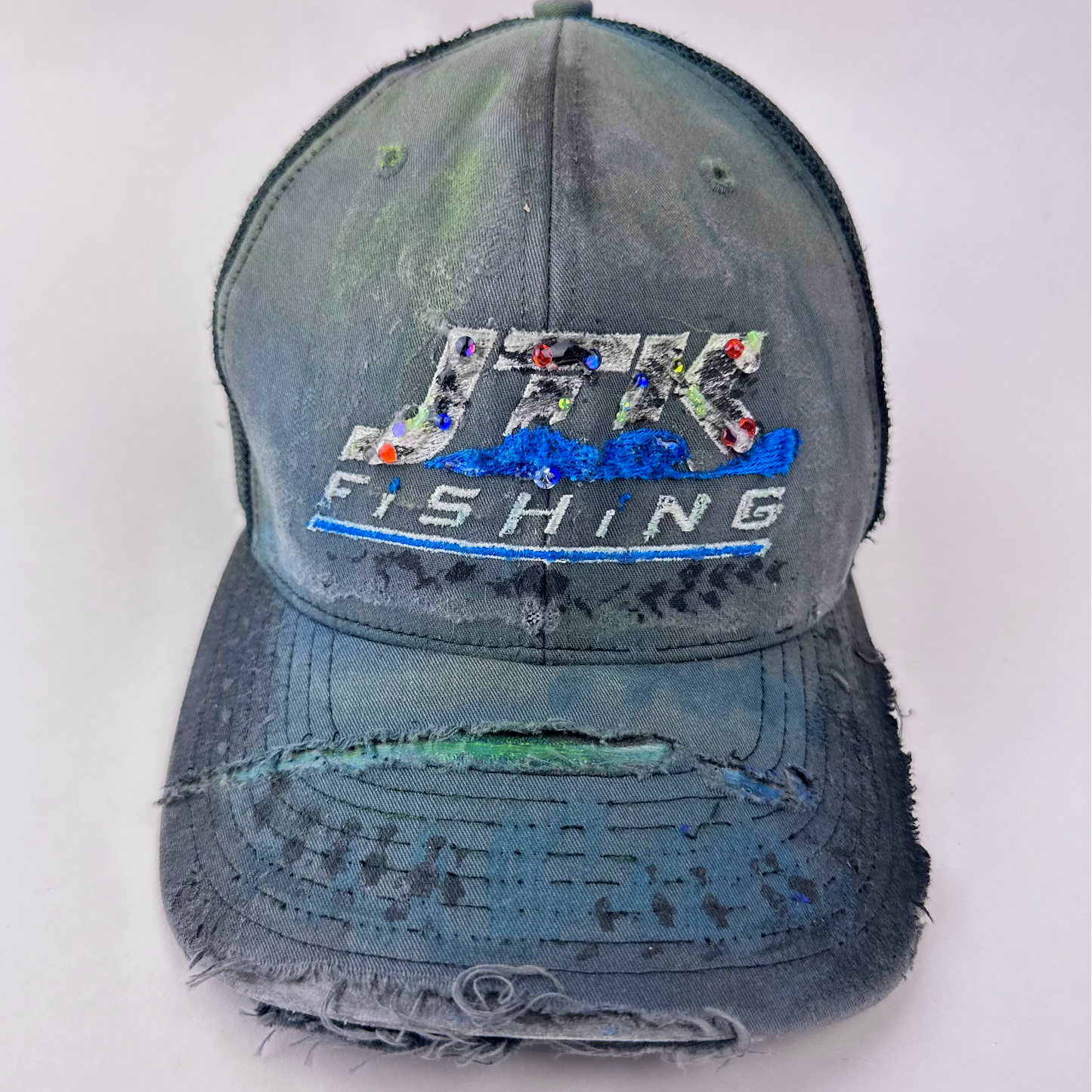 ASTROBOI* 'JFK Fishing' gray rhinestone trucker cap with rhinestone-embellished embroidered logo, blue wave design, and deconstructed visor, front view.
