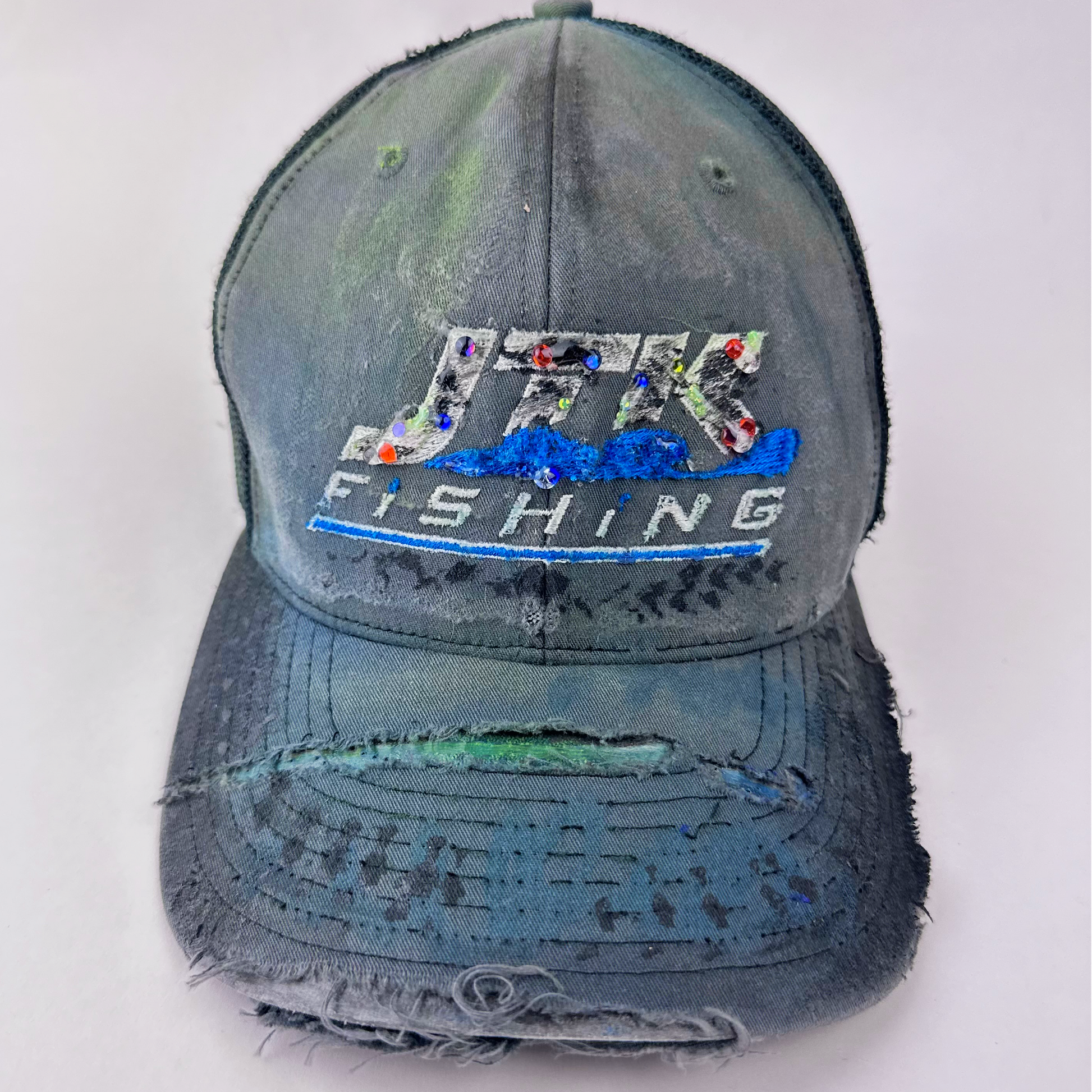 ASTROBOI* 'JFK Fishing' gray rhinestone trucker cap with rhinestone-embellished embroidered logo, blue wave design, and deconstructed visor, front view.