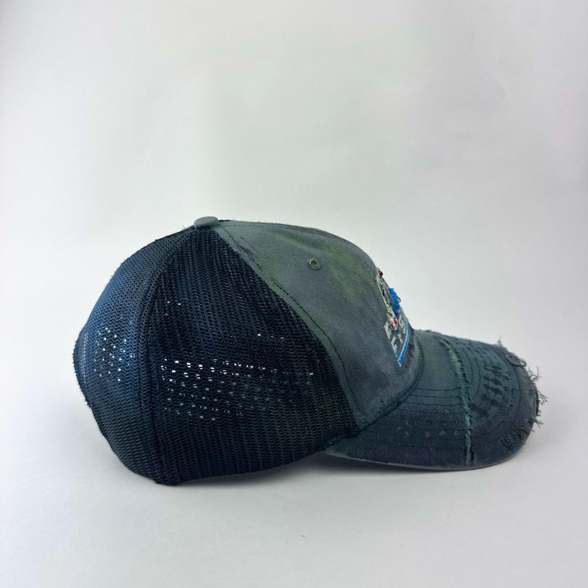 Right side detail of ASTROBOI* 'JFK Fishing' showing multicolor paint treatment and deconstructed visor on gray trucker base.