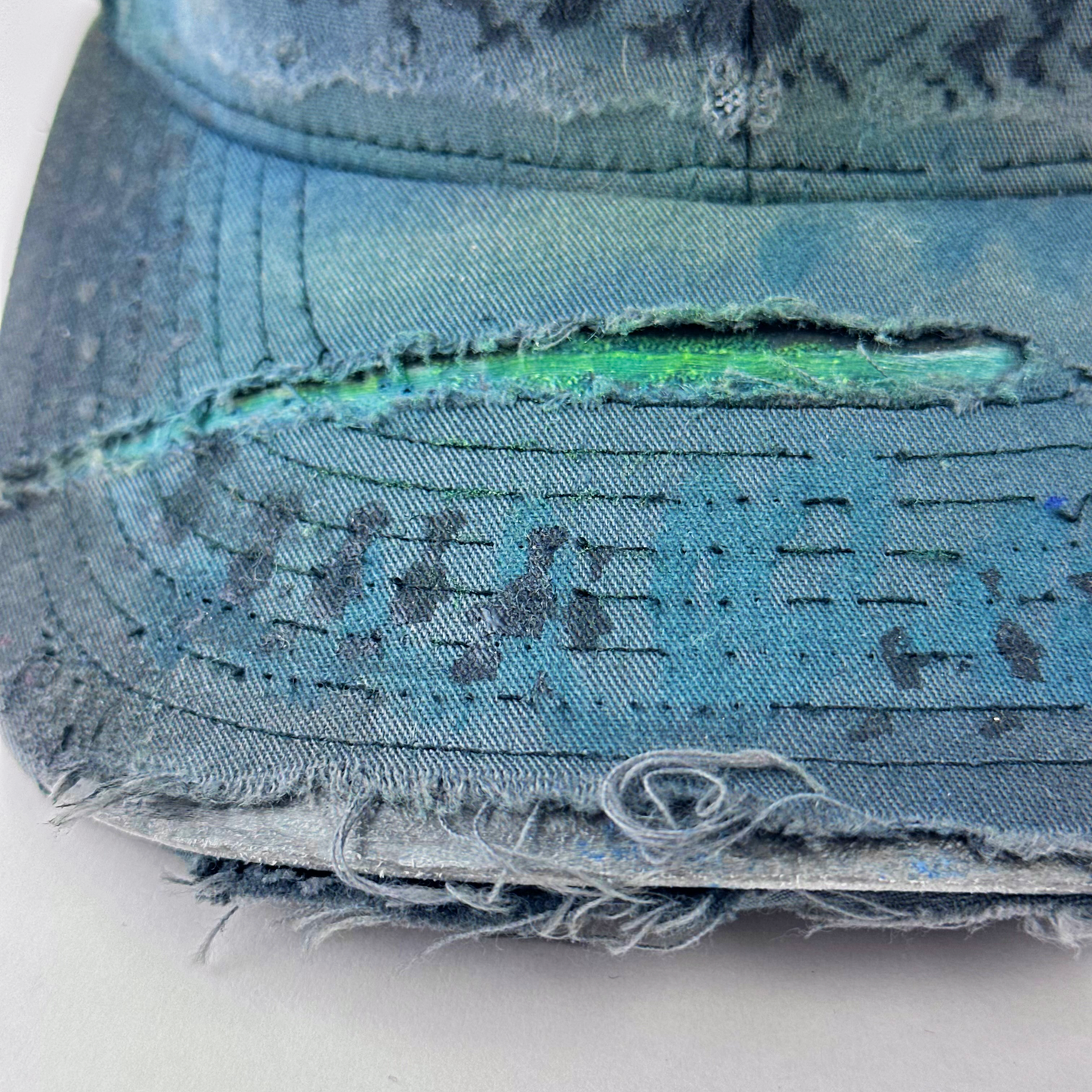ASTROBOI* 'JFK Fishing' gray rhinestone trucker cap with rhinestone-embellished embroidered logo, blue wave design, and deconstructed visor, visor detail.
