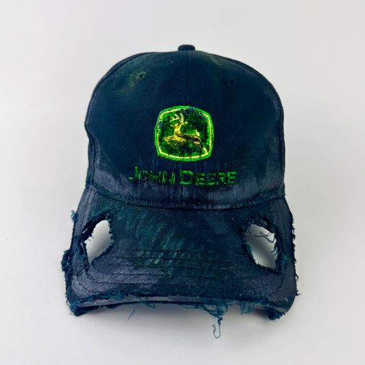 ASTROBOI* x John Deere 'Hyland' black distressed cut out hat with John Deere green and yellow logo patch at front, custom paint treatment, and cut-outs along the visor, front view.