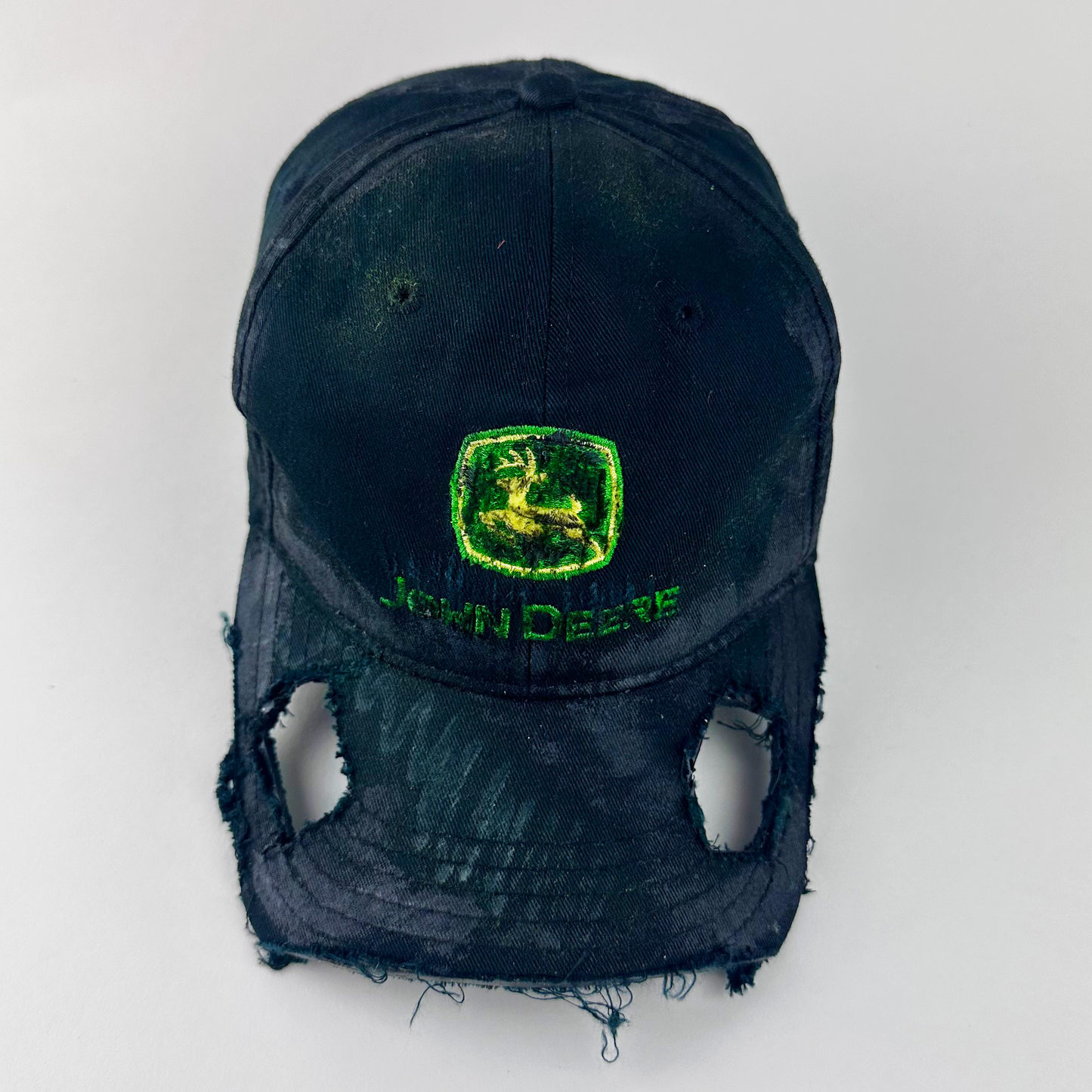 ASTROBOI* x John Deere 'Hyland' black distressed cut out hat with John Deere green and yellow logo patch at front, custom paint treatment, and cut-outs along the visor, front view.