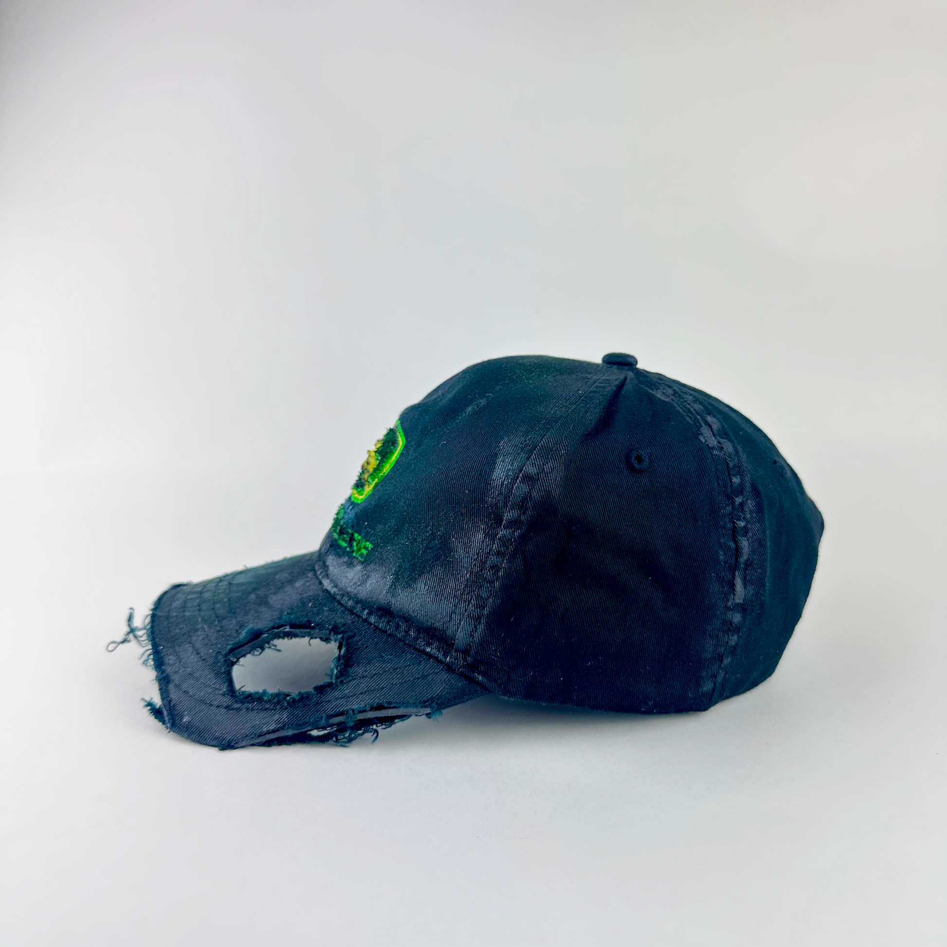Left side detail of ASTROBOI* x John Deere 'Hyland' showing cut-out visor detail and custom paint treatment on distressed black John Deere hat.