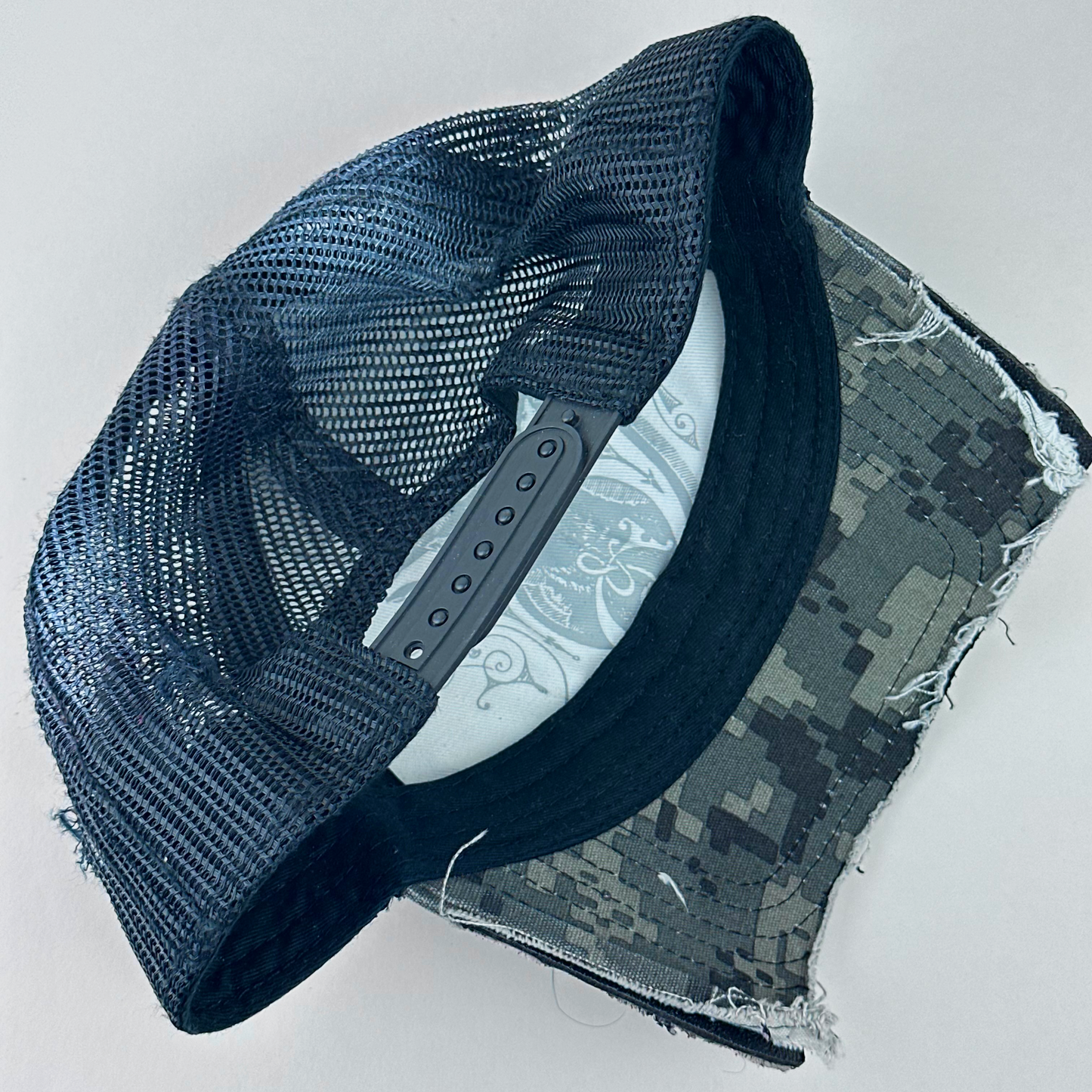 ASTROBOI* x John Deere 'Silver Surf' black digital camo trucker hat, rear view showing black mesh back panel and adjustable strap.