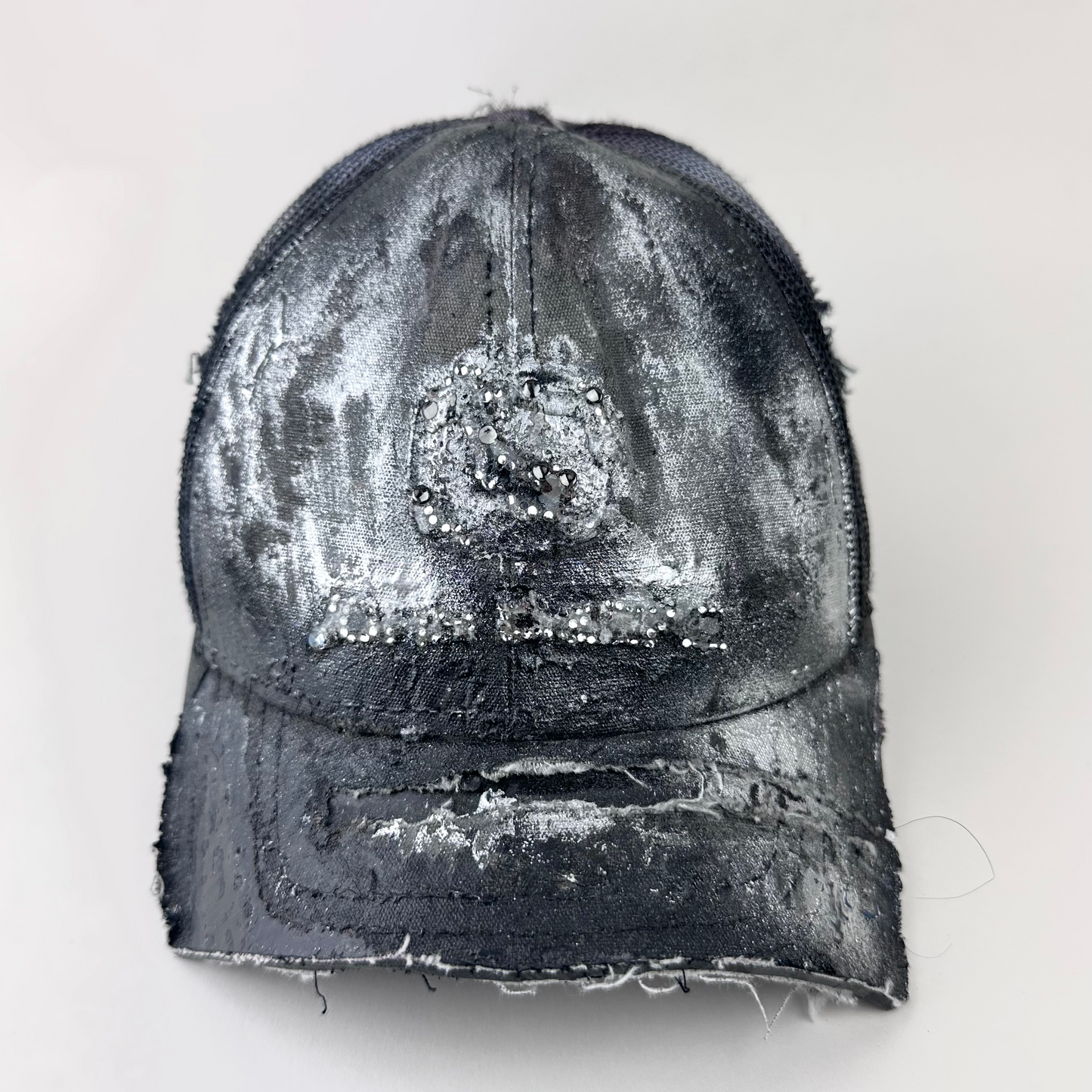 ASTROBOI* x John Deere 'Silver Surf' black digital camo trucker hat with silver tonal rhinestone-embellished John Deere logo and partially sawed-off deconstructed visor, front view.